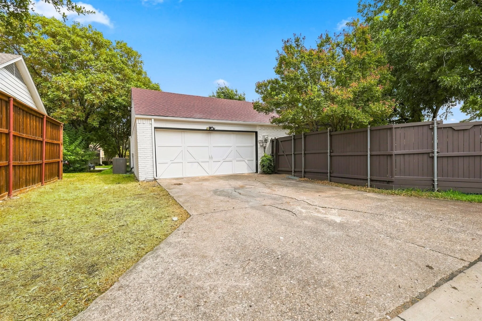 Attached two-car garage with a white panel door, concrete driveway, and a brick exterior
