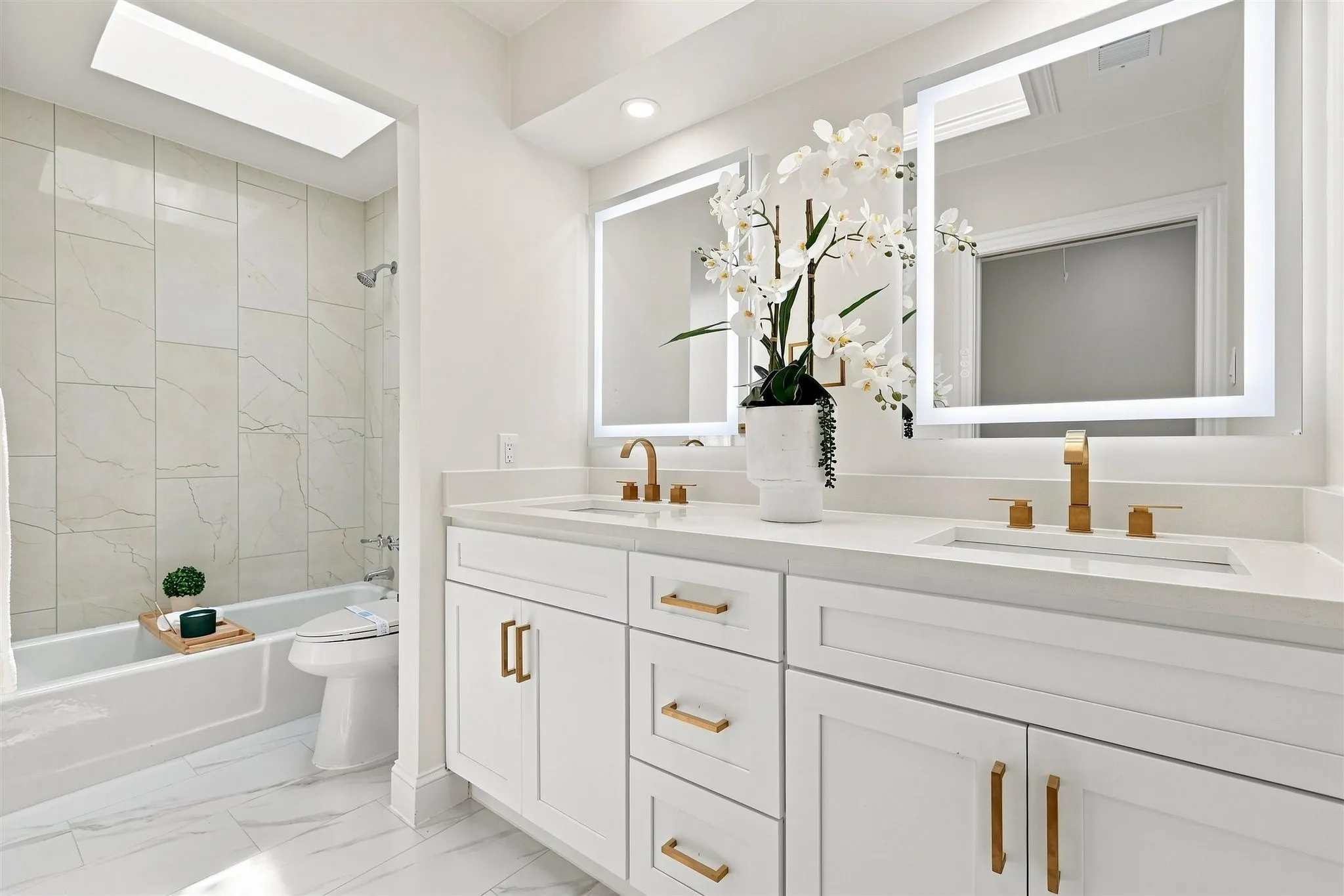 Dual vanity with white shaker cabinetry and gold-tone hardware