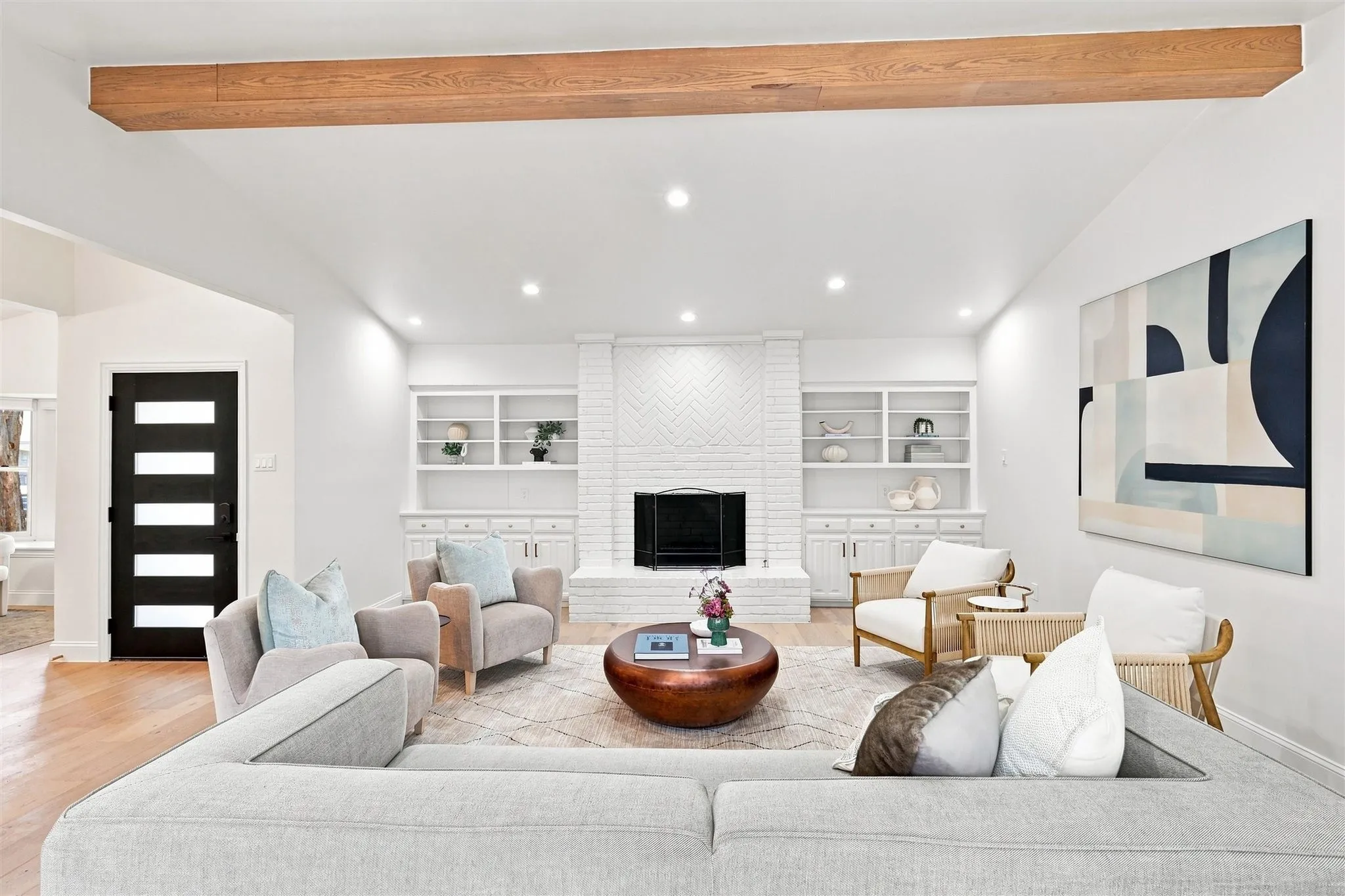 Exposed wood beam, recessed lighting, fireplace with white brick surround, built-in shelving, wood-finish flooring