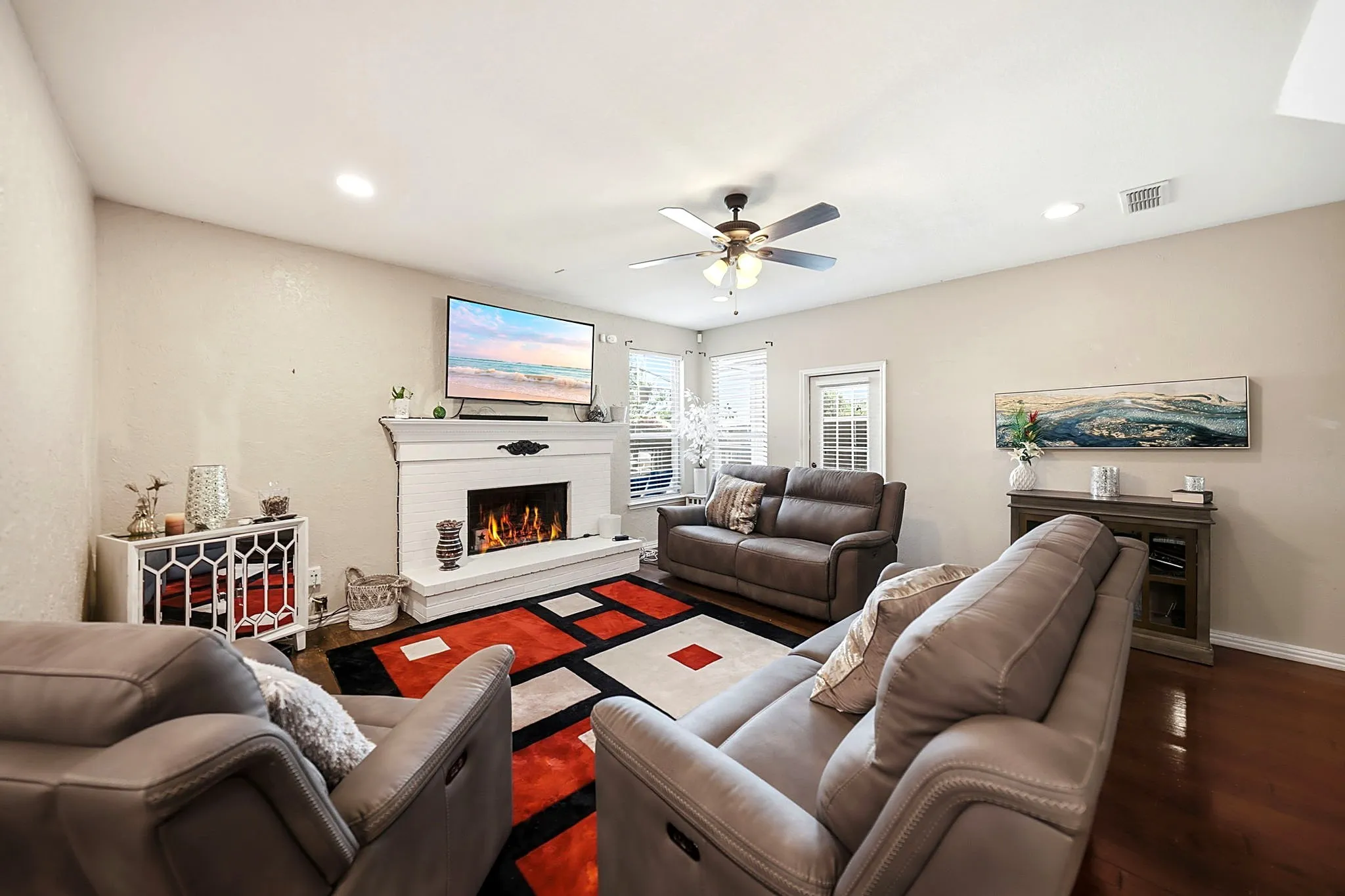 Living area featuring a white brick fireplace with a mantel, wood-finish flooring, and recessed lighting