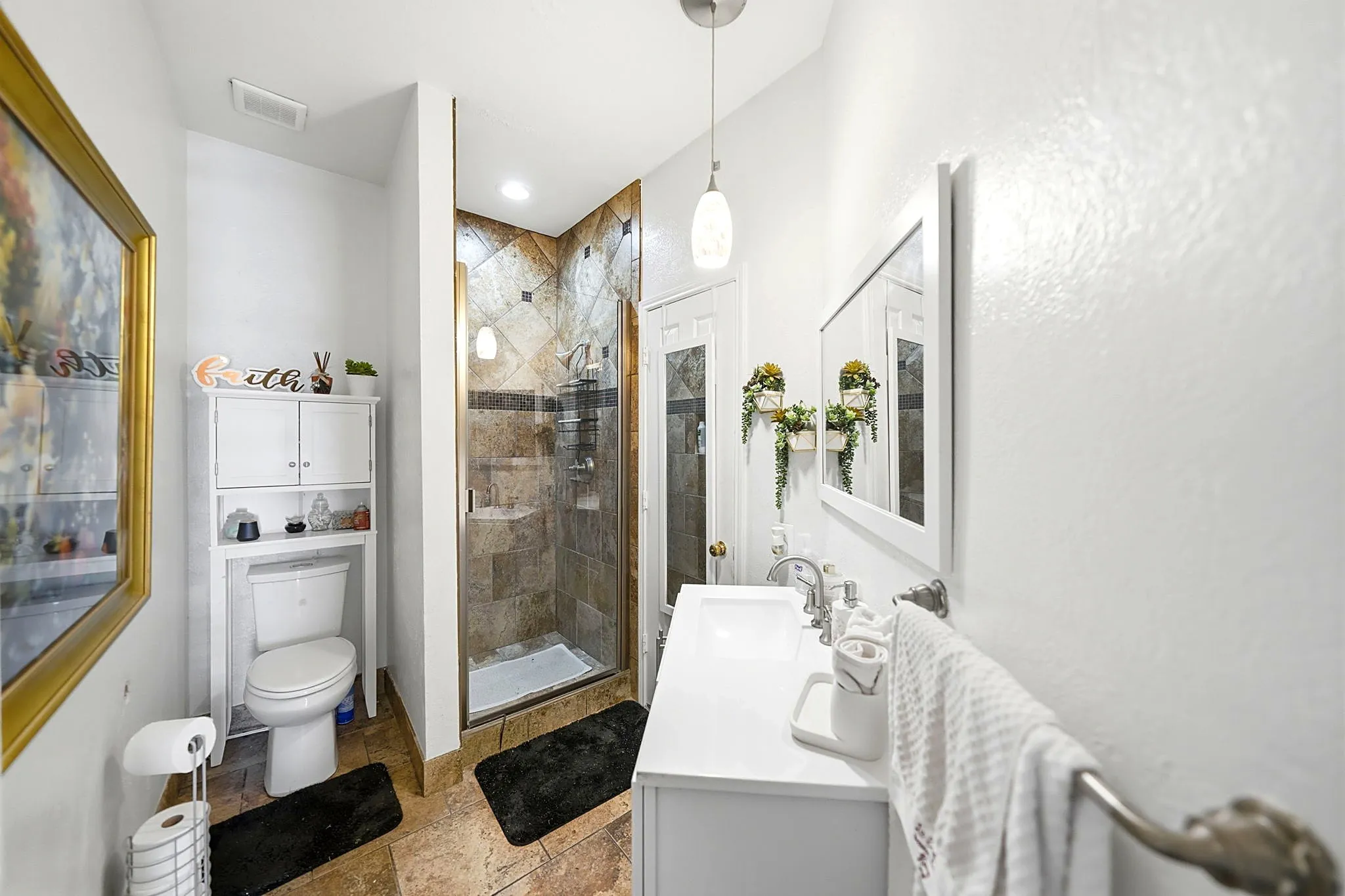 White vanity with dual sinks, framed mirror, and pendant lighting