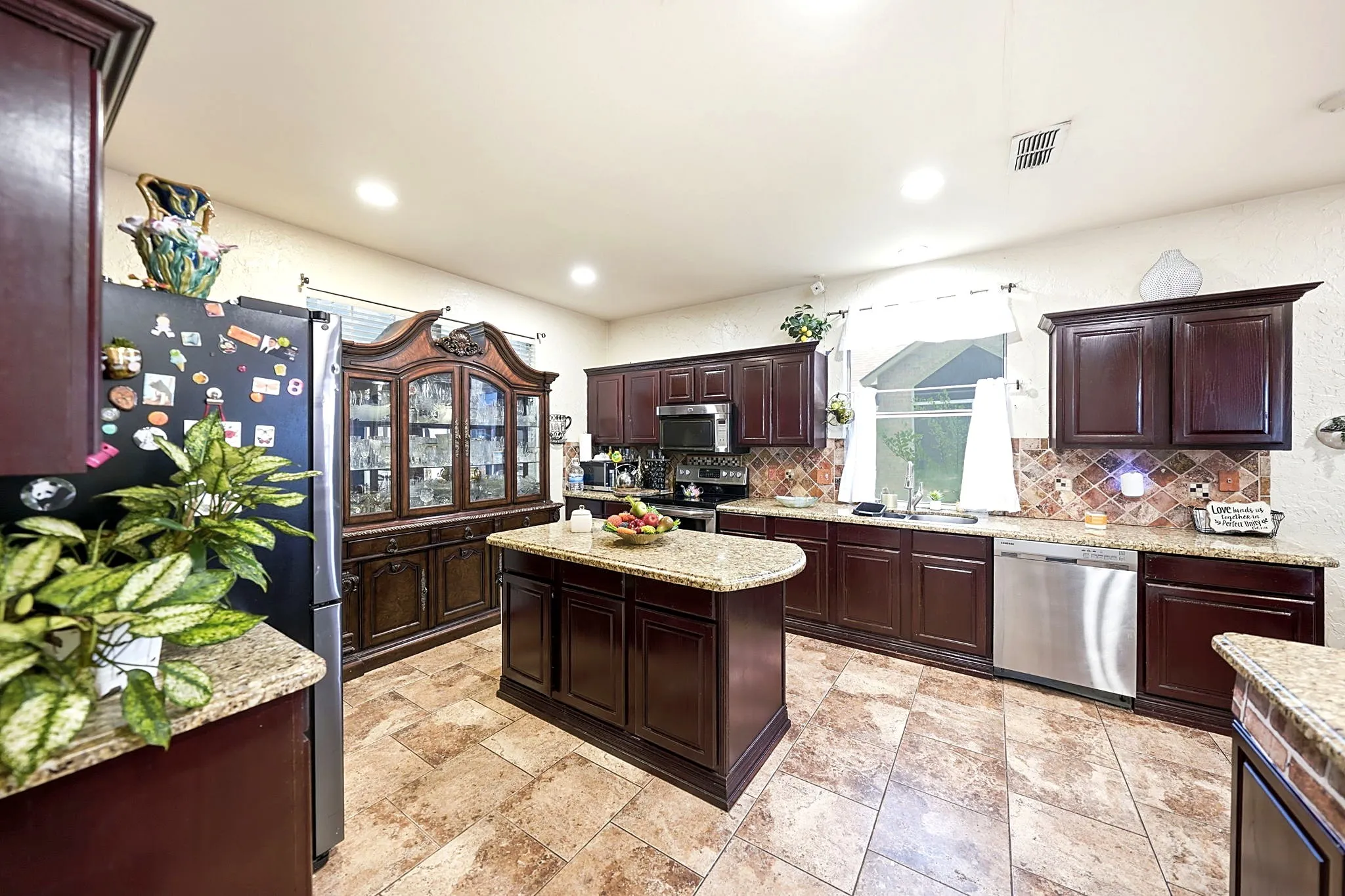 Kitchen featuring dark wood-finish cabinetry, granite-style countertops, mosaic tile backsplash, a central island, and recessed lighting