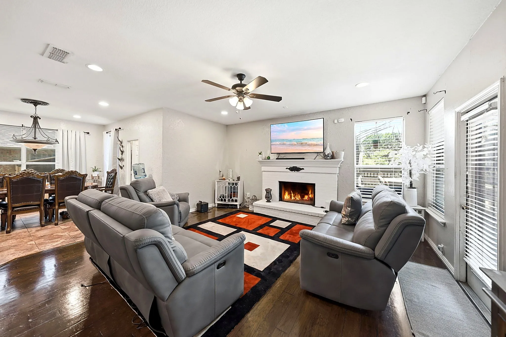 Living area featuring a fireplace with a mantel, dark wood-finish flooring, recessed lighting, and a ceiling fan
