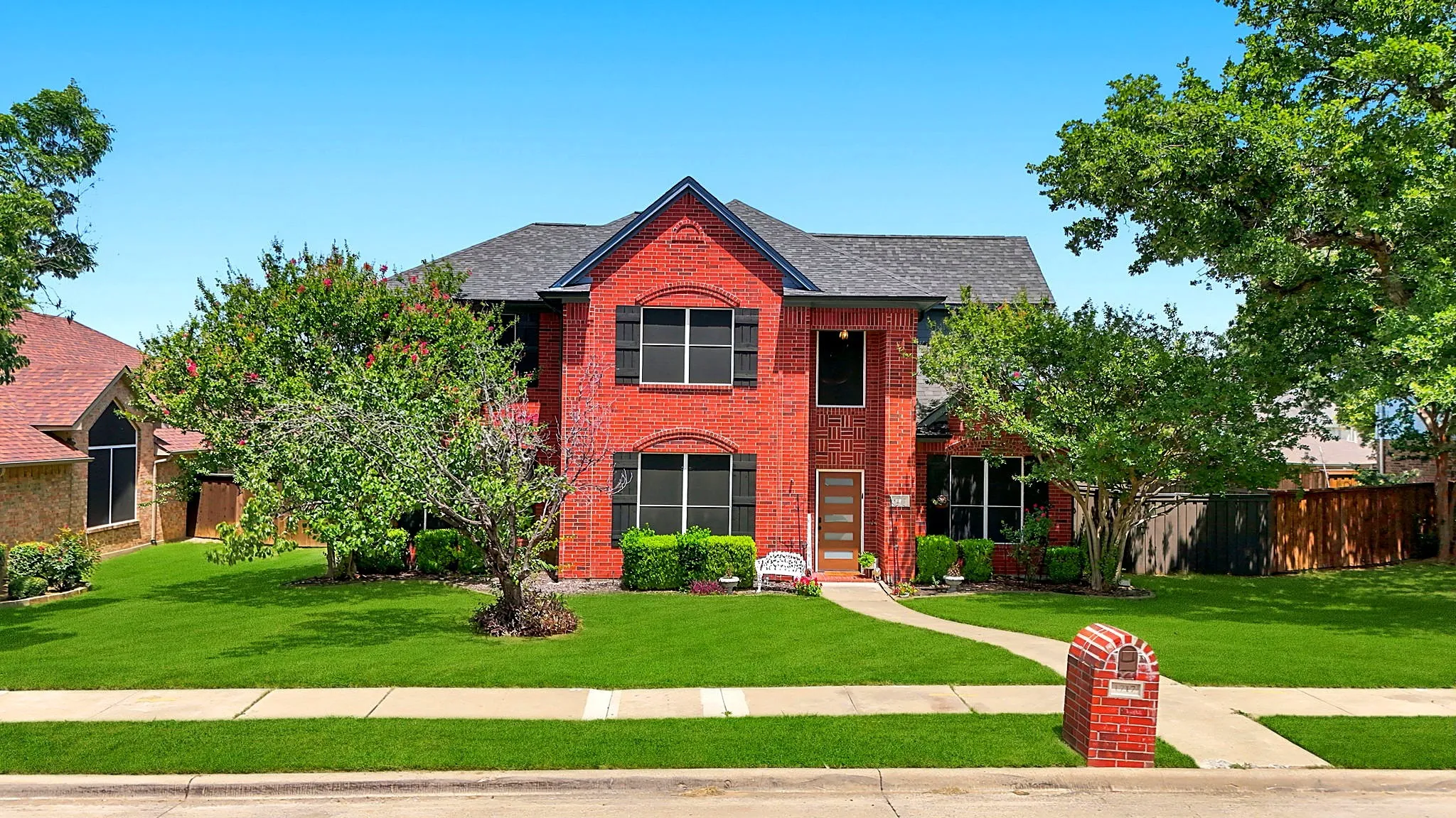 Red brick exterior with dark shingle roof and black shutters
