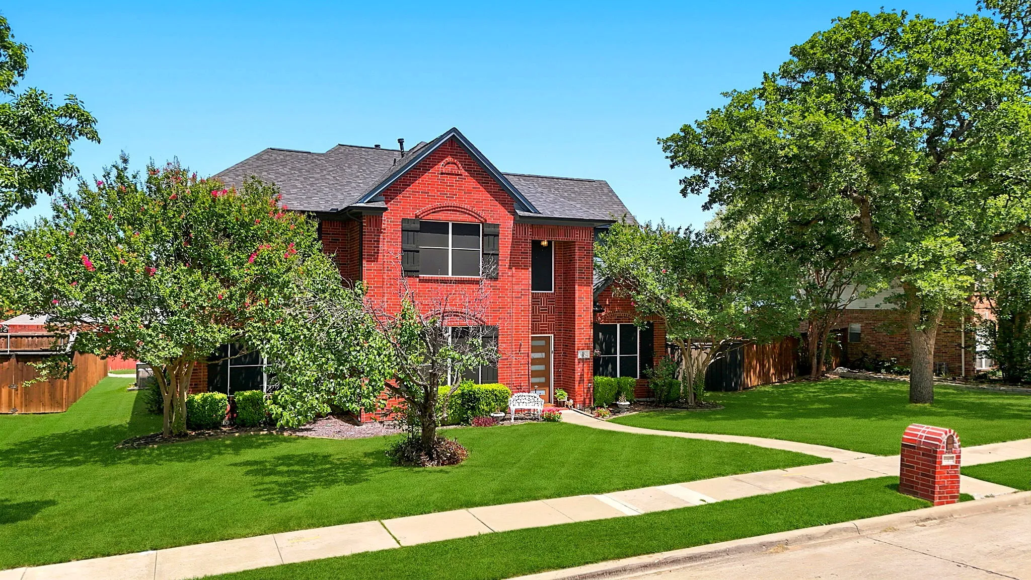 Red brick exterior with dark shutters, gabled roofline, and established landscaping