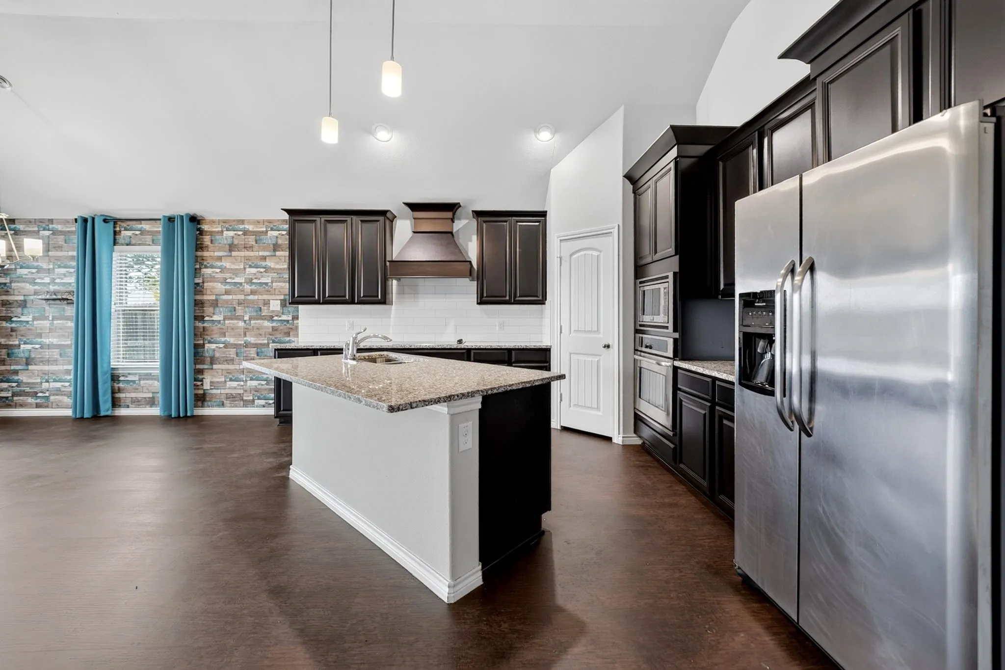 Kitchen featuring dark wood-finish cabinetry, stainless steel appliances, a center island with a granite-style countertop, and recessed lighting