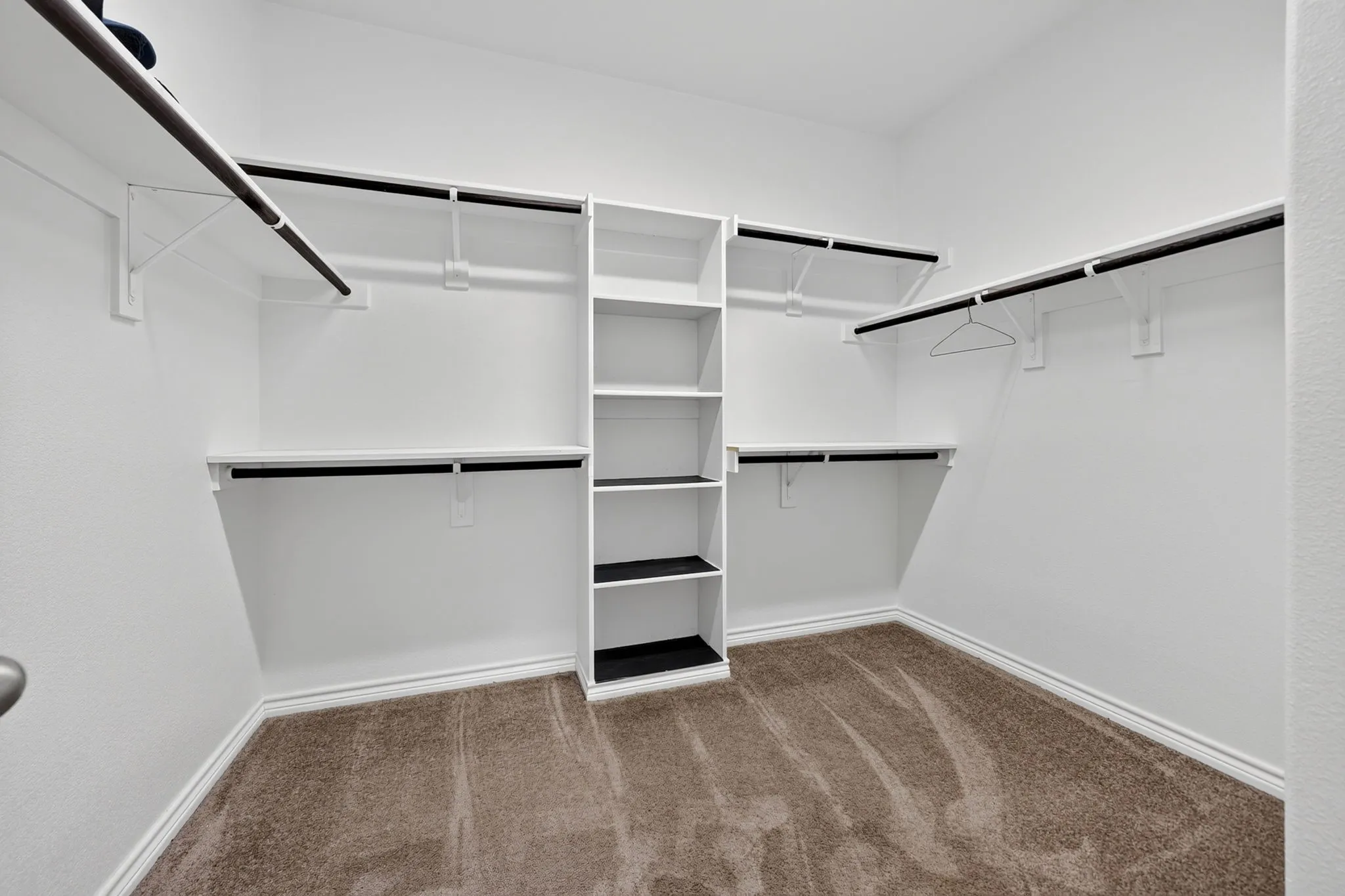 Expansive walk-in closet with integrated shelving and multiple hanging rods for organization