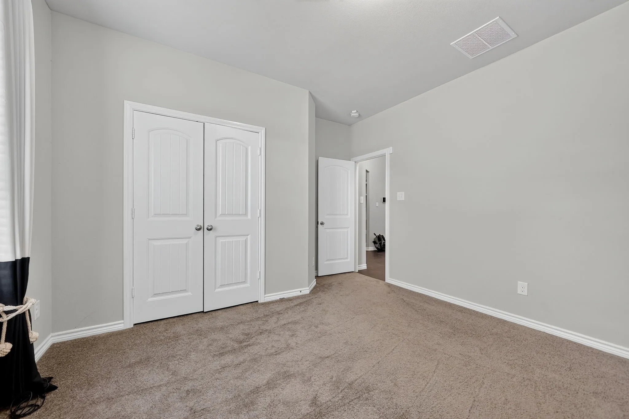 Carpeted room featuring light gray walls, white trim, and white bi-fold doors with round hardware