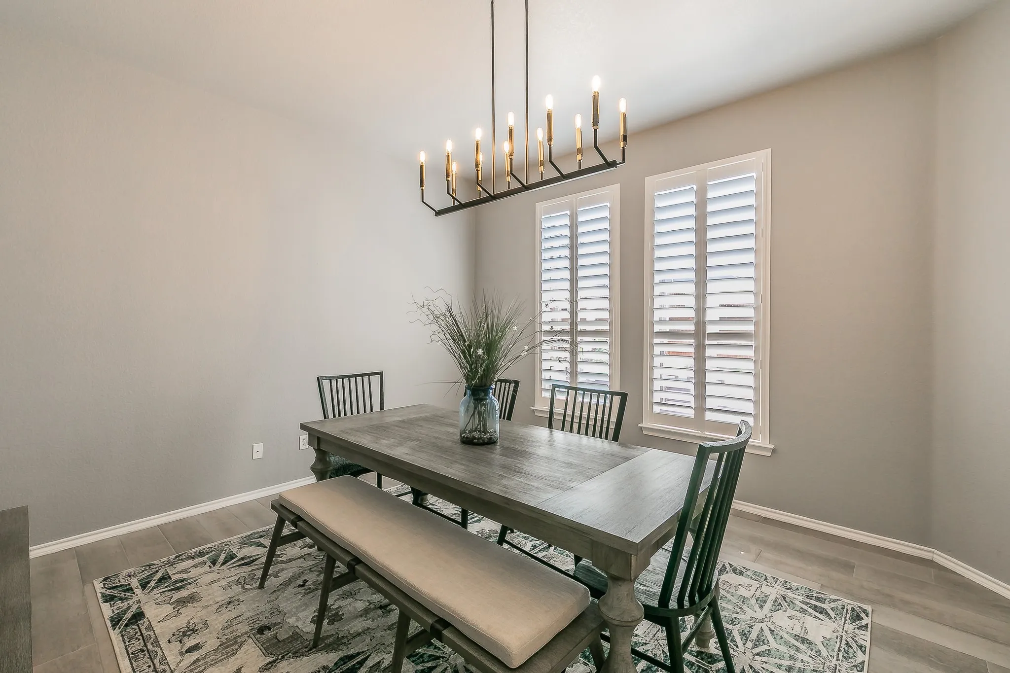 Formal Dining room. Wood-finish flooring, crisp white trim, and a linear chandelier featuring multiple light sources