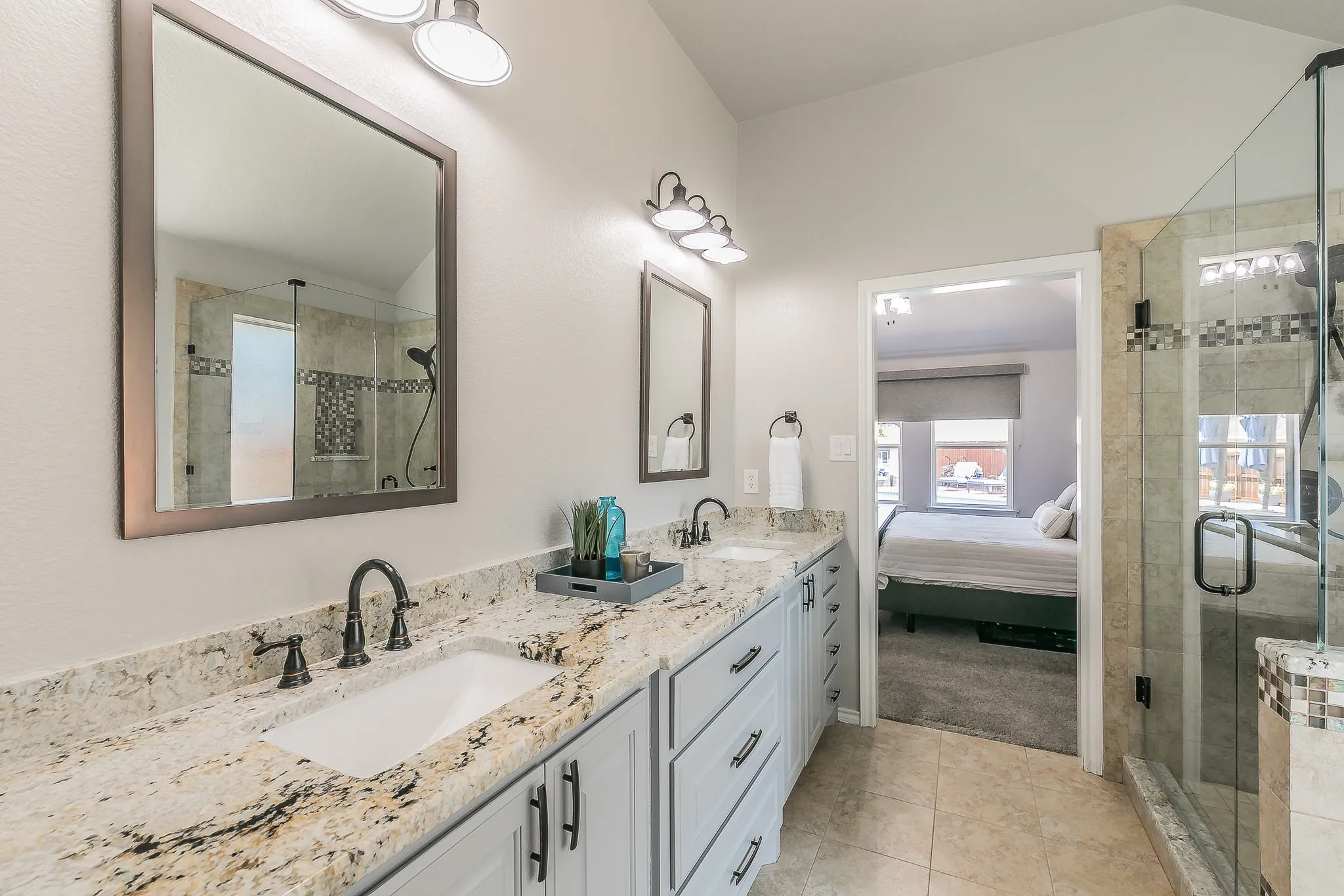 Dual vanity with granite countertops, light-finish cabinetry, and matte black fixtures