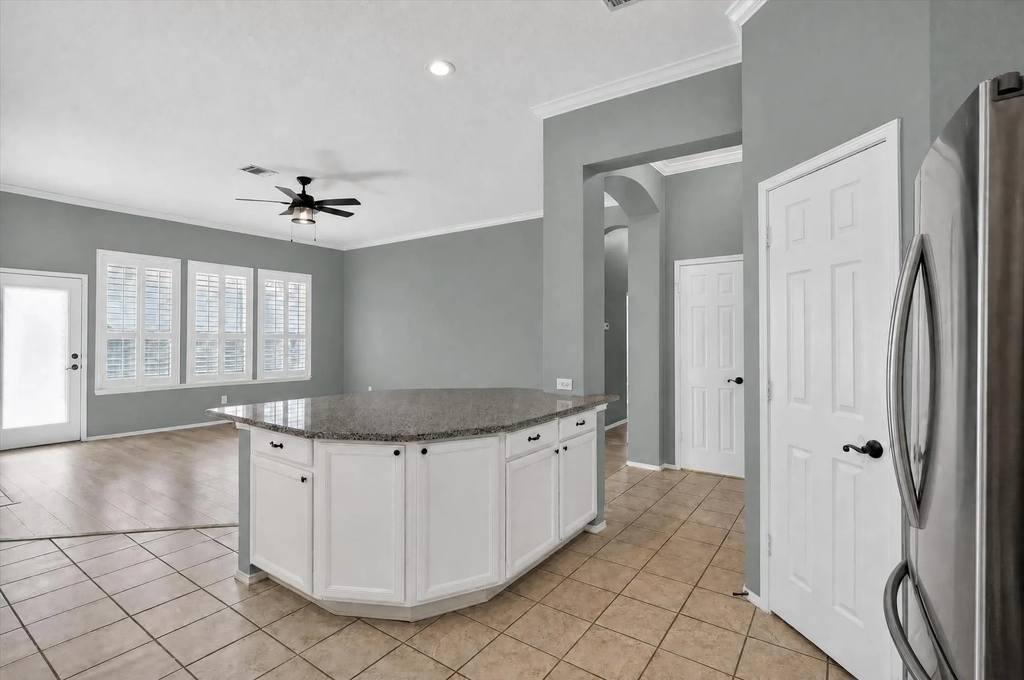 Kitchen island with granite-finish countertop and white cabinetry