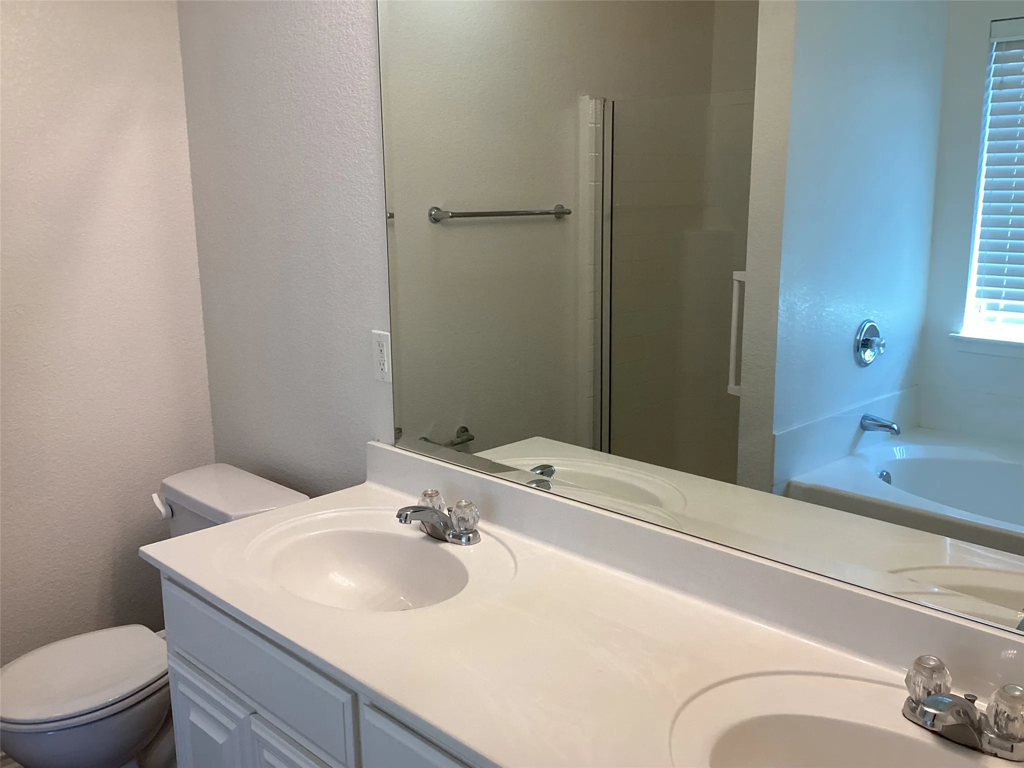 Double vanity with integrated sinks, full-width mirror, built-in bathtub, and separate shower enclosure
