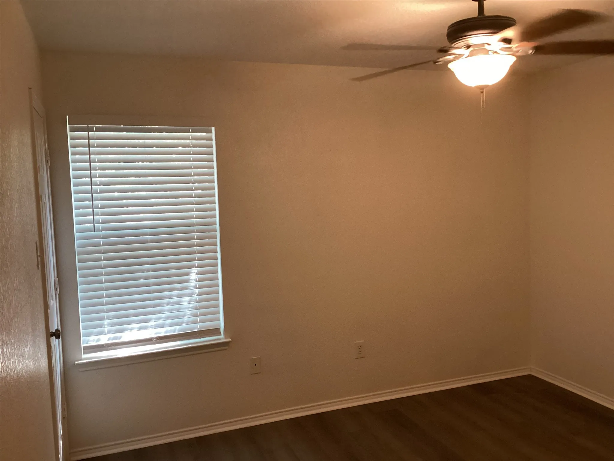 Window with blinds, wood-finish flooring, ceiling fan with integrated lighting, and neutral wall tones