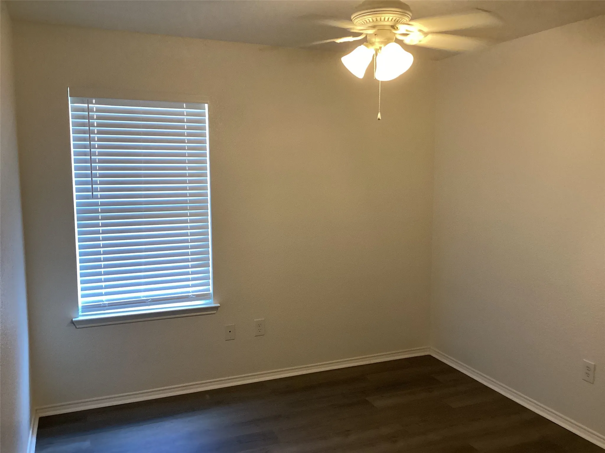 Wood-finish flooring, white walls, and a window with horizontal blinds