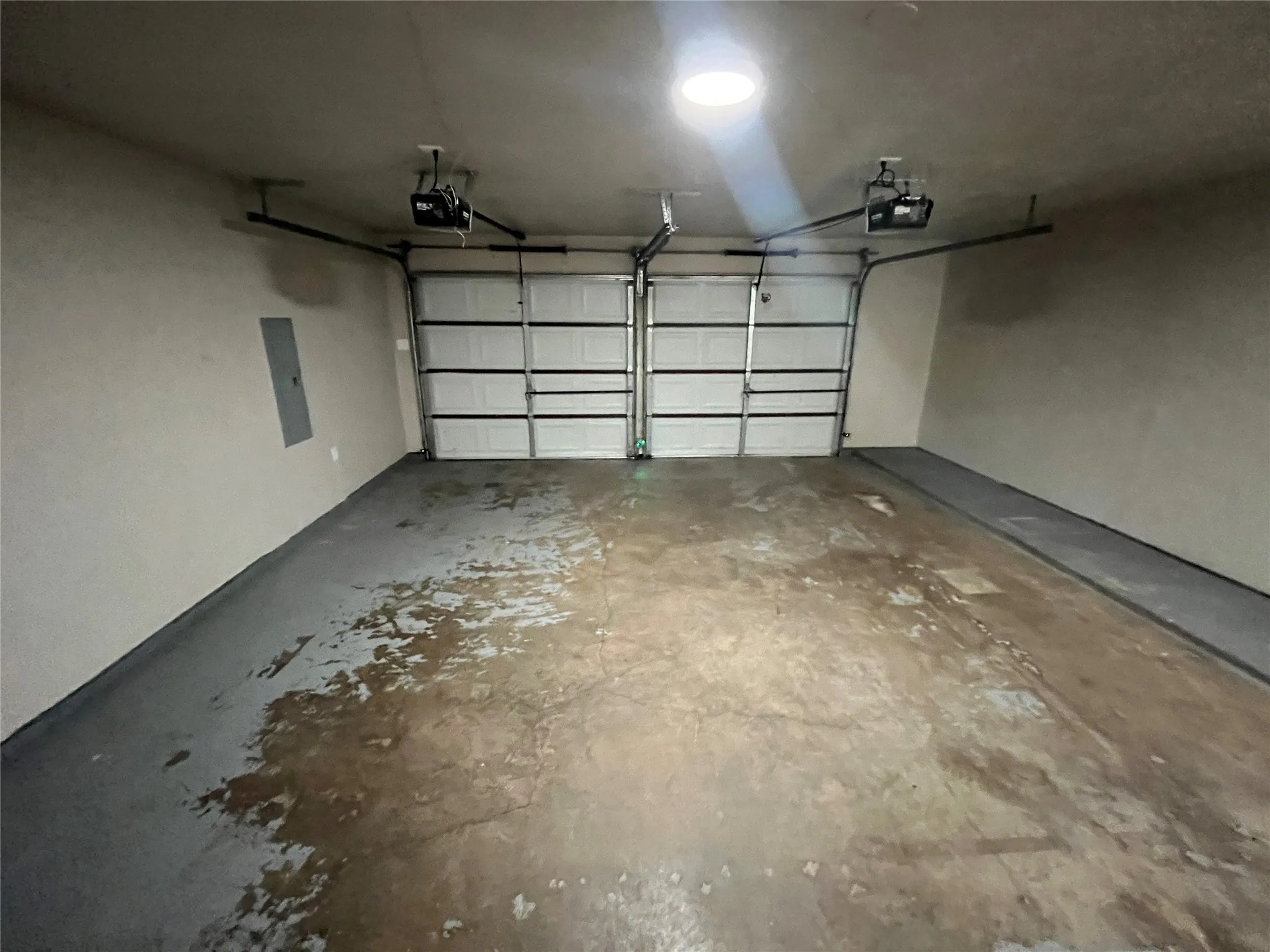 Two-car garage featuring automatic door openers, a wall-mounted electrical panel, and an overhead light fixture
