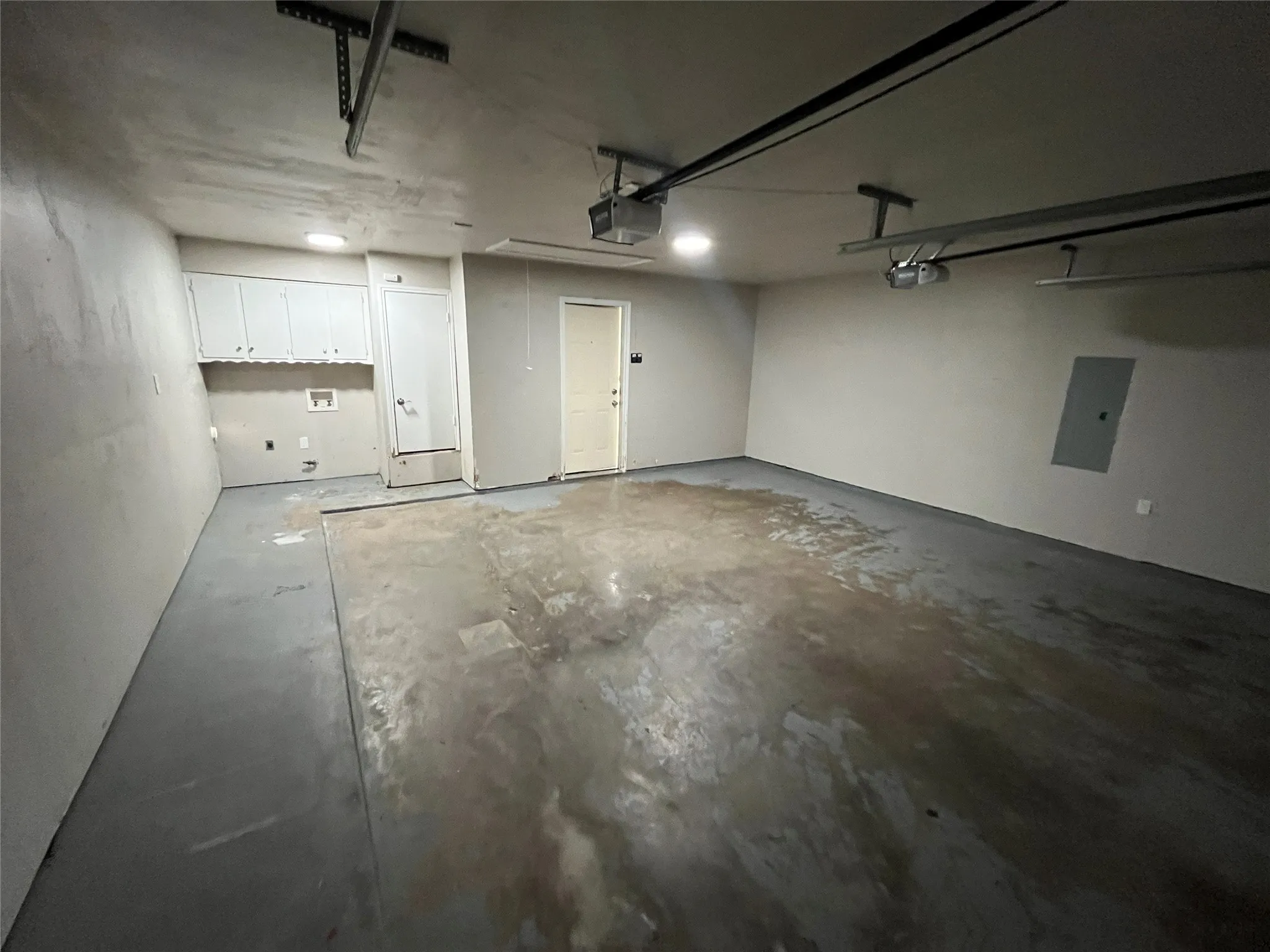 Attached garage featuring overhead lighting, multiple garage door openers, and built-in cabinetry