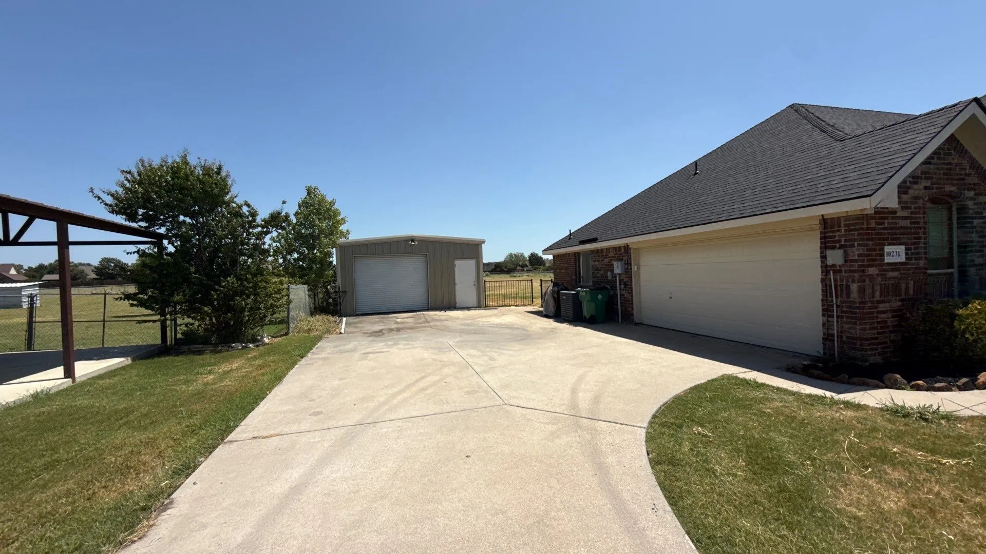 Concrete driveway leading to an attached two-car garage and a detached metal building