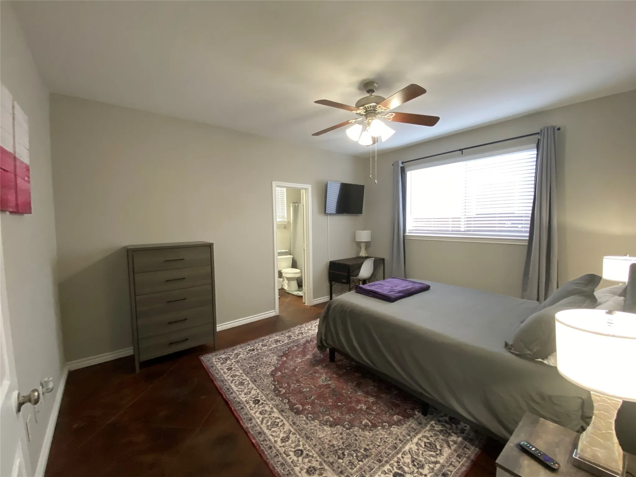 Wood-finish flooring with a ceiling fan light fixture and a window with blinds