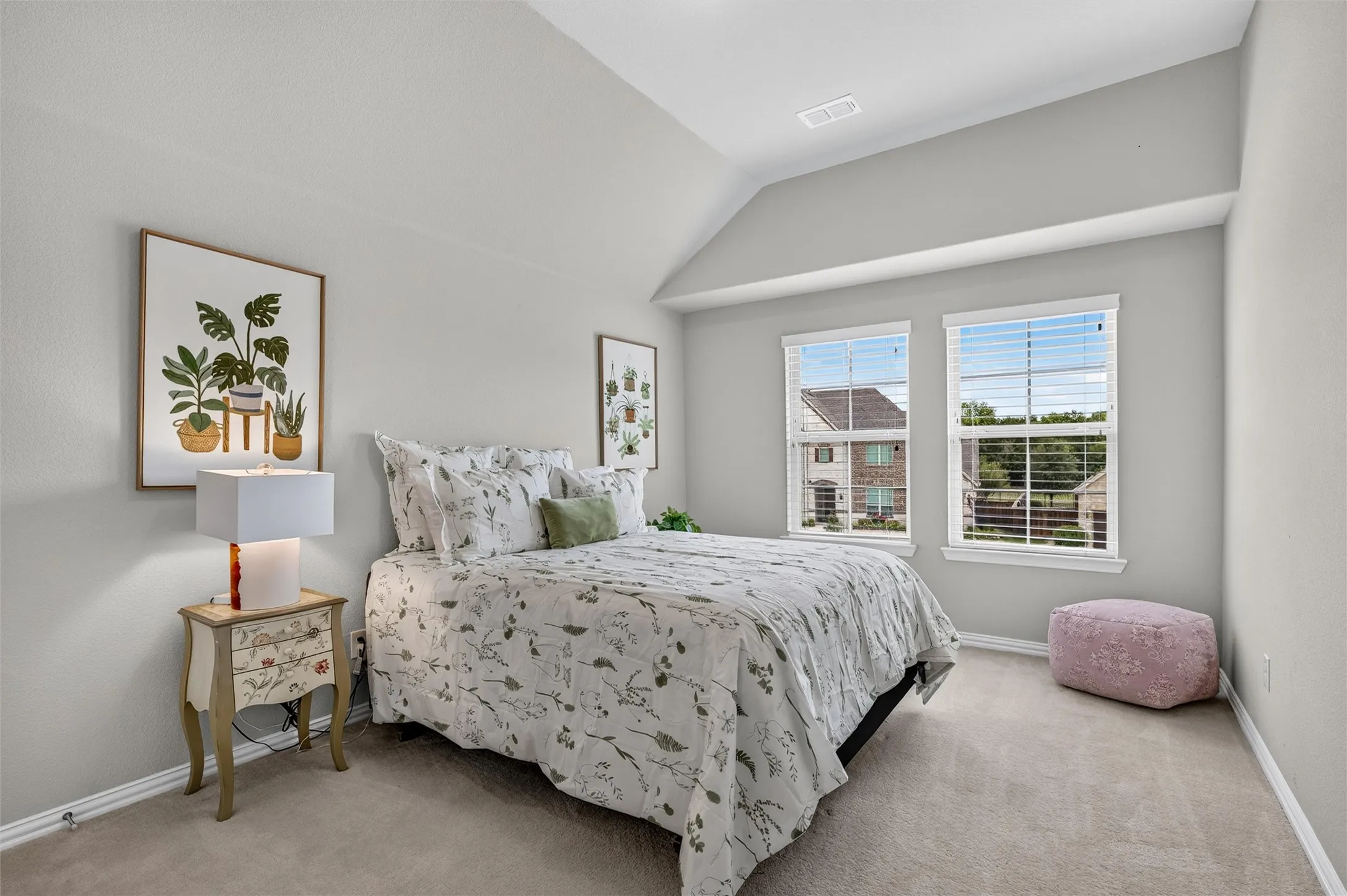 Carpeted flooring with painted walls, twin windows with blinds, and a vaulted ceiling