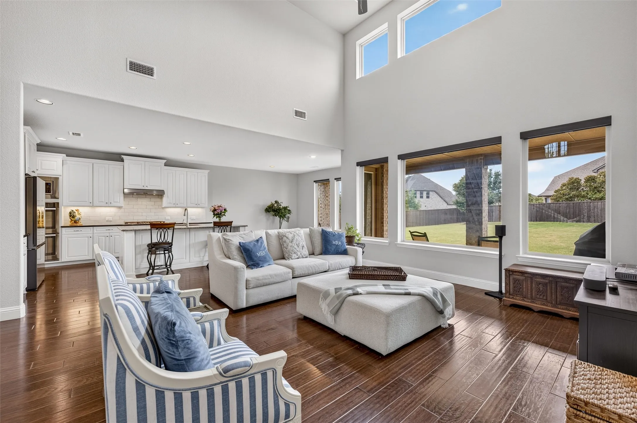 Two-story living area with high ceilings, wood-finish flooring, and multiple windows