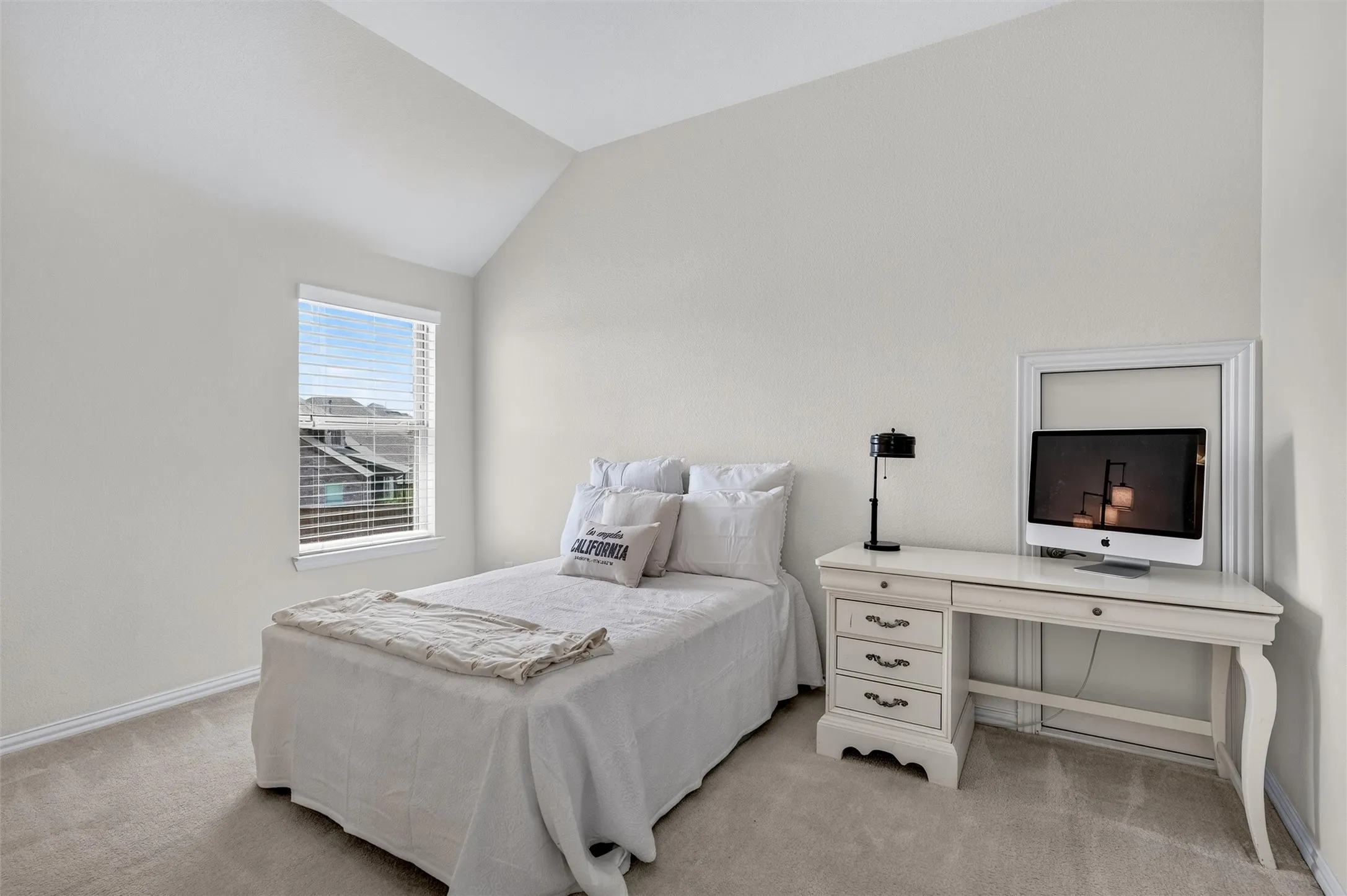 Vaulted ceiling with a single window, neutral wall paint, and light-colored carpeting
