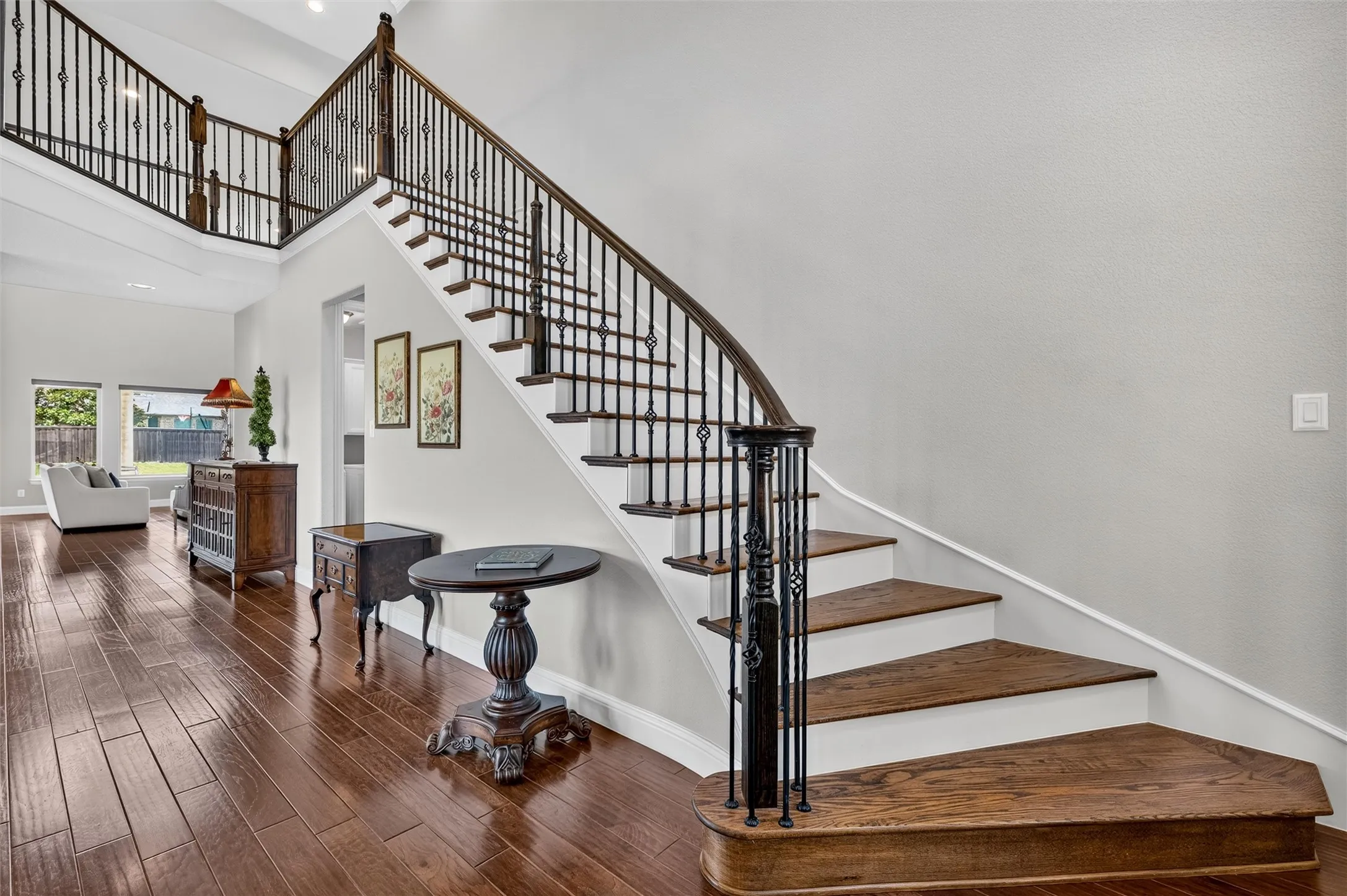 Curved staircase with wrought iron balusters and wood-finish treads