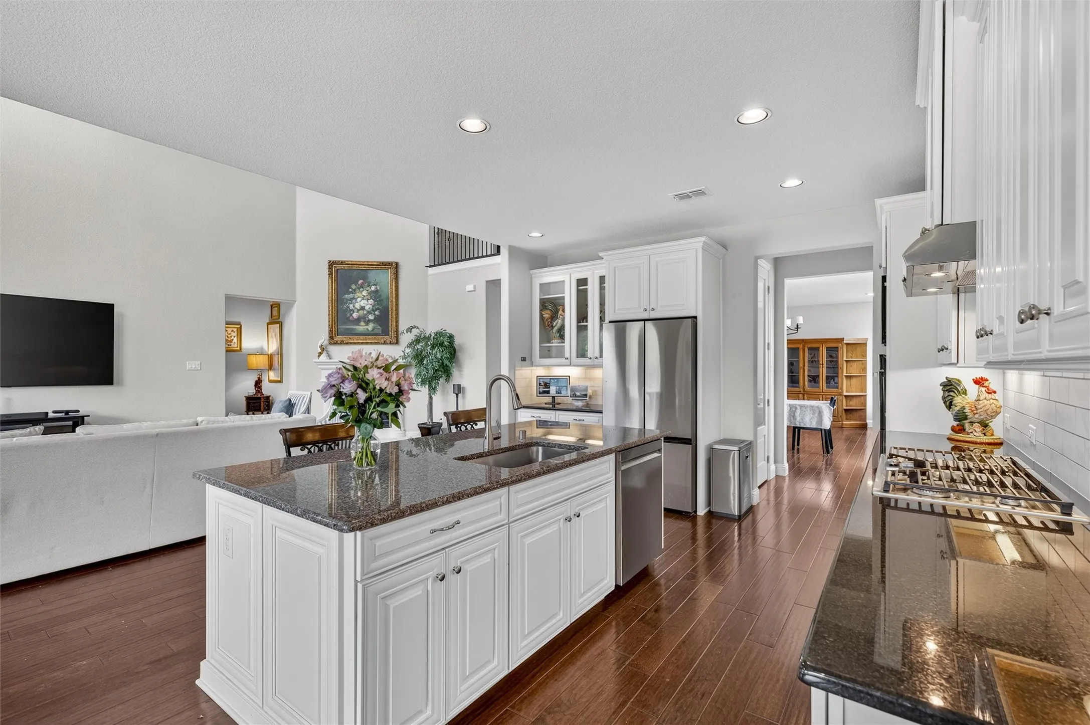 Kitchen featuring white cabinetry, dark stone countertops, stainless steel appliances, and wood-finish flooring
