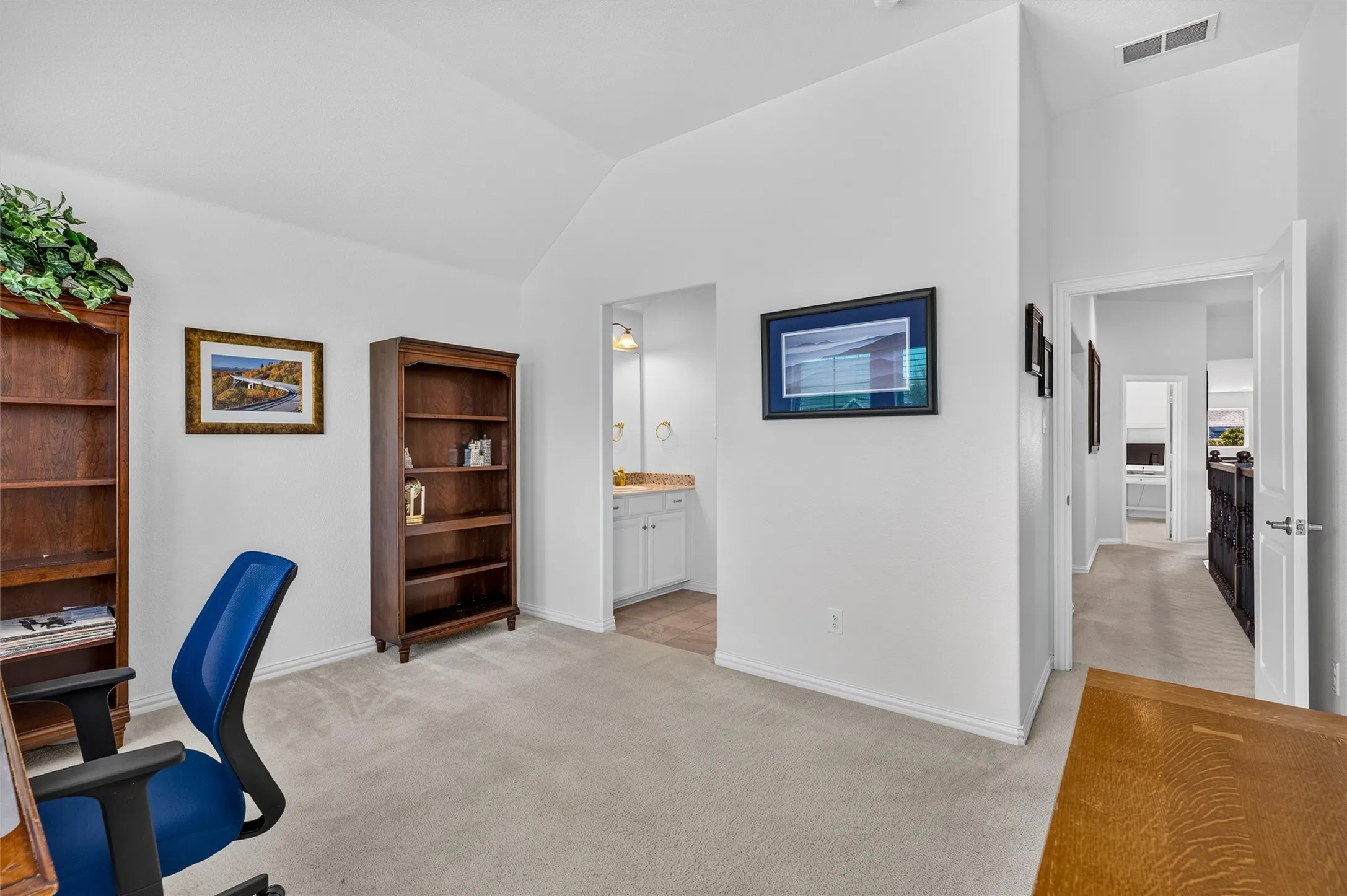 Vaulted ceiling, light-toned carpeting, white painted walls, and an open doorway