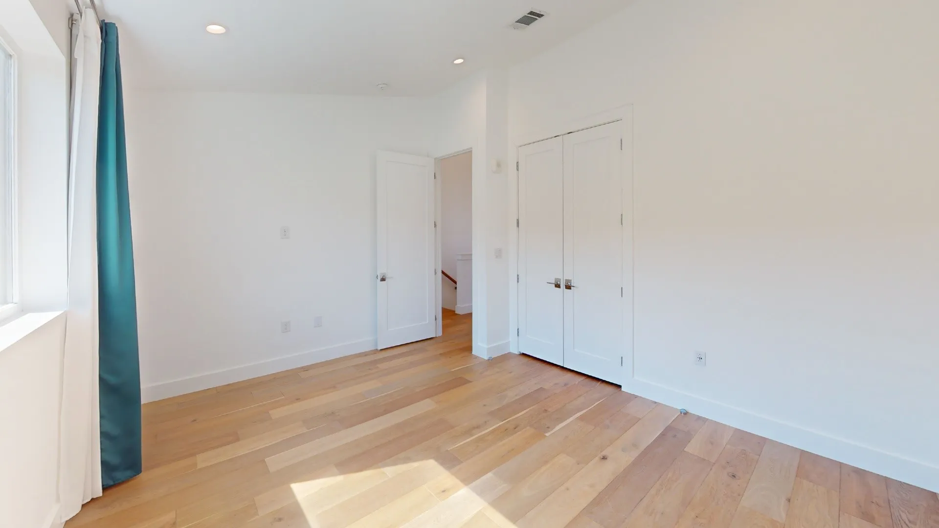 Hardwood-style flooring, white walls, recessed ceiling lighting, and a white window frame