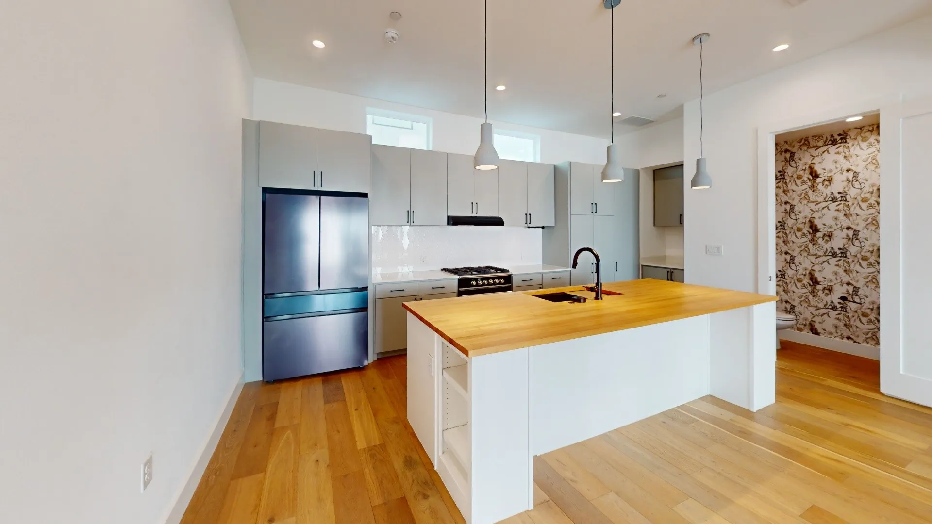 Kitchen featuring an expansive island with a wood-finish countertop, undermount sink, and pendant lighting