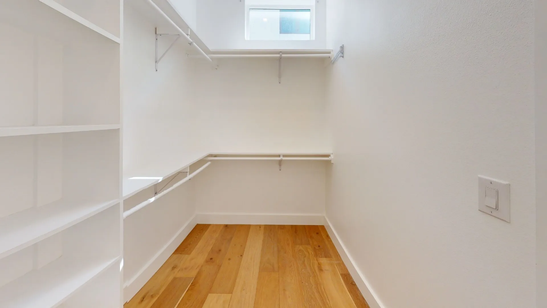 Walk-in closet with wood-finish flooring, built-in shelving, and hanging rods