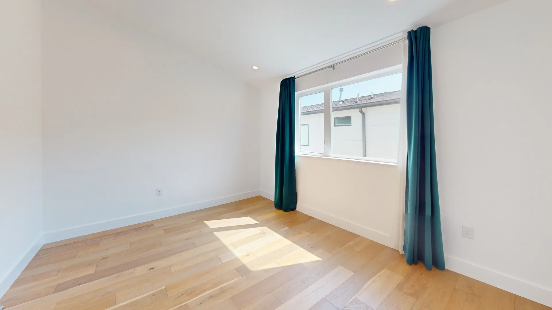 Recessed ceiling lighting, light wood-finish flooring, white walls, and a large window