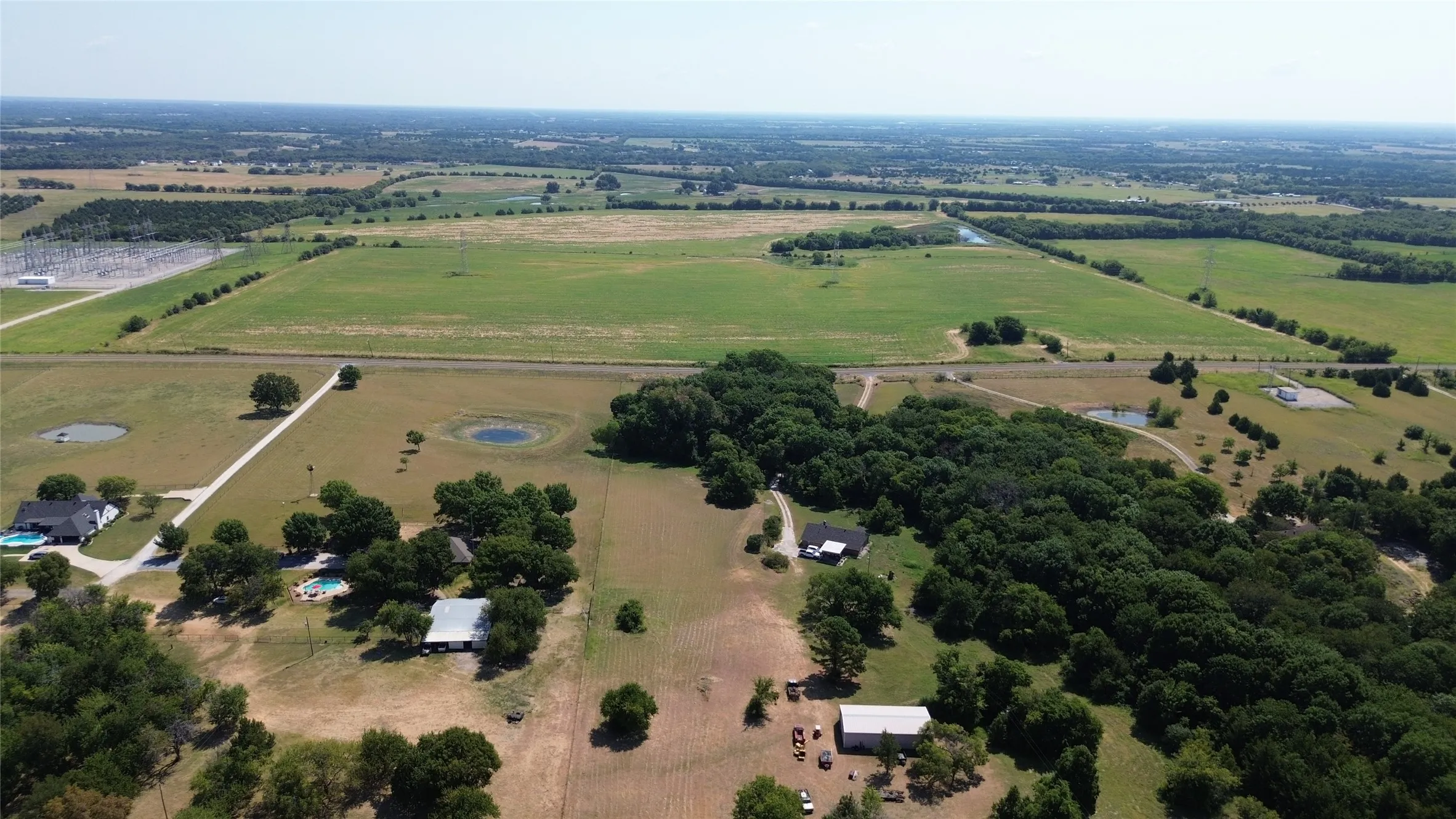 Expansive acreage featuring multiple fields, wooded areas, and a visible pond