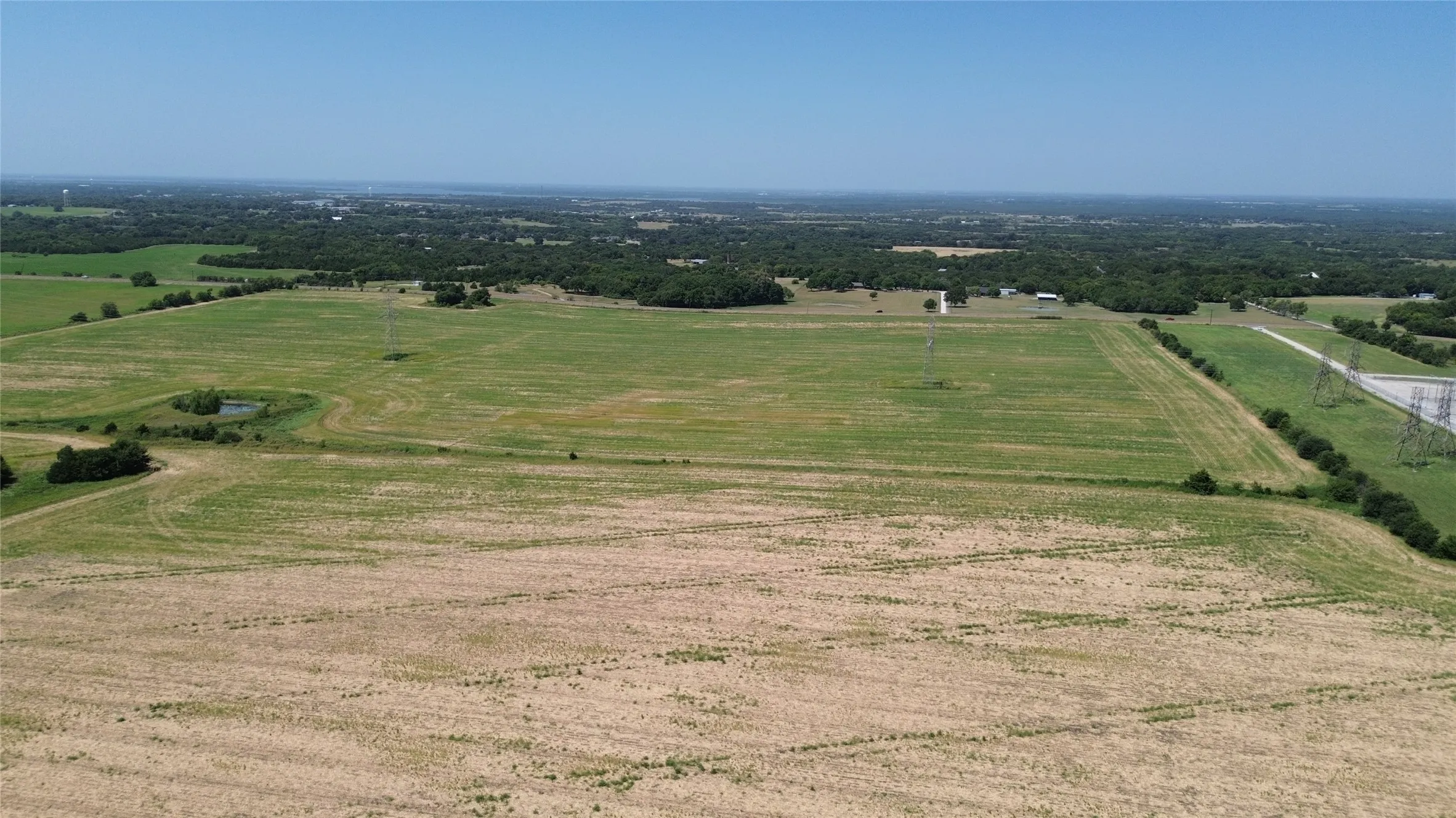 Expansive land featuring open fields, distant treelines, and clear skies