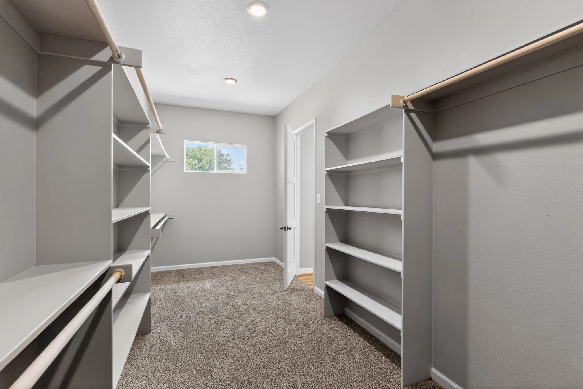 Walk-in closet featuring built-in shelving, hanging rods, recessed lighting, and a window for natural illumination