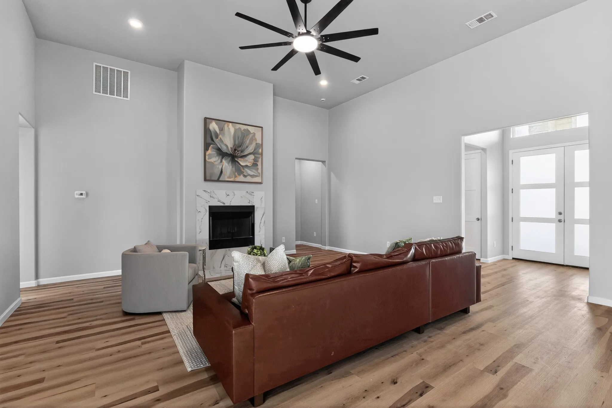 Spacious living area featuring a fireplace with a light-toned marble surround, vaulted ceilings, and recessed lighting