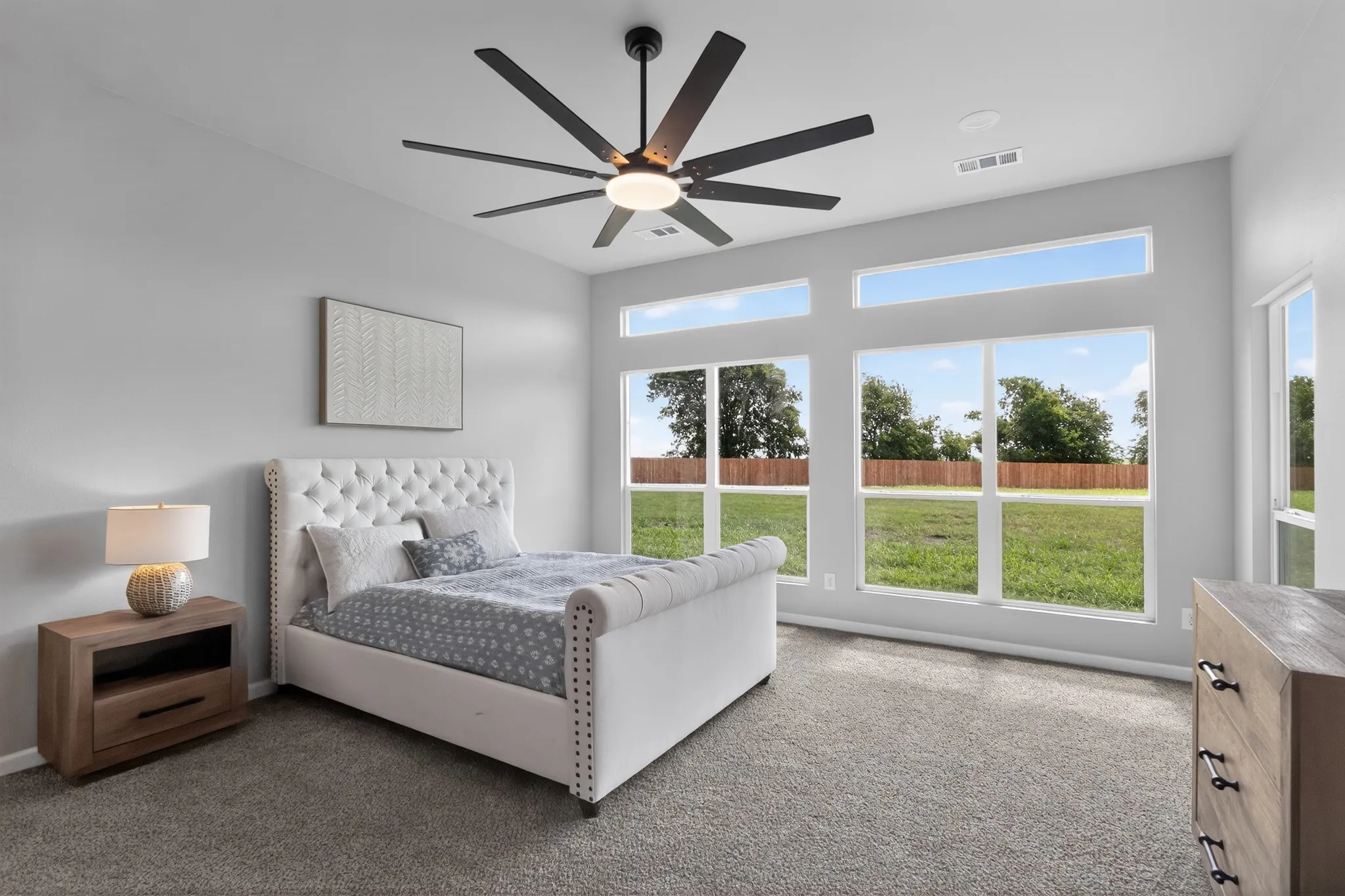 Spacious room featuring multiple large windows, high ceilings, and a modern ceiling fan with integrated lighting