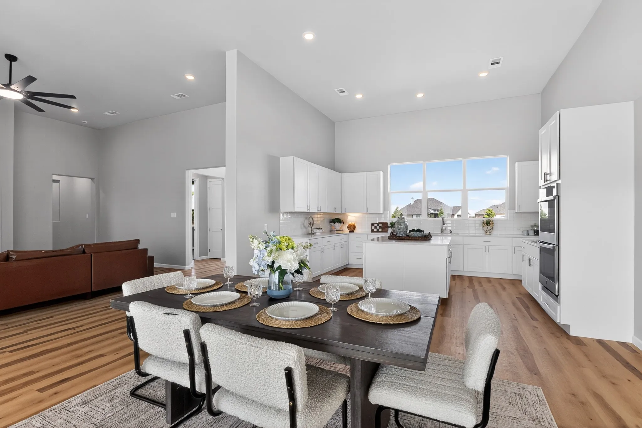 Open-concept living space with wood-finish flooring, recessed lighting, and high ceilings