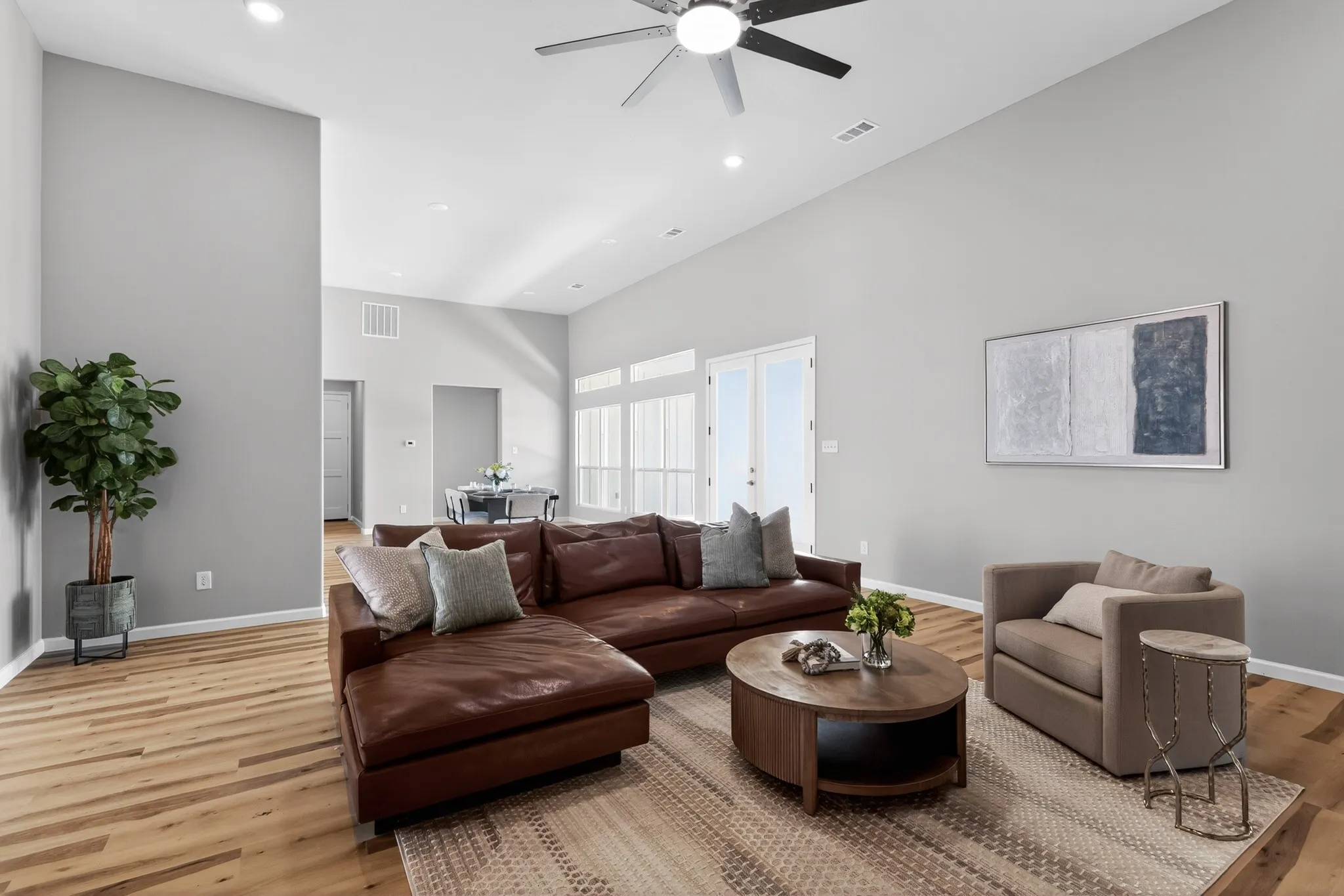 Spacious living area featuring high vaulted ceilings, recessed lighting, wood-finish flooring, and white double glass pane doors