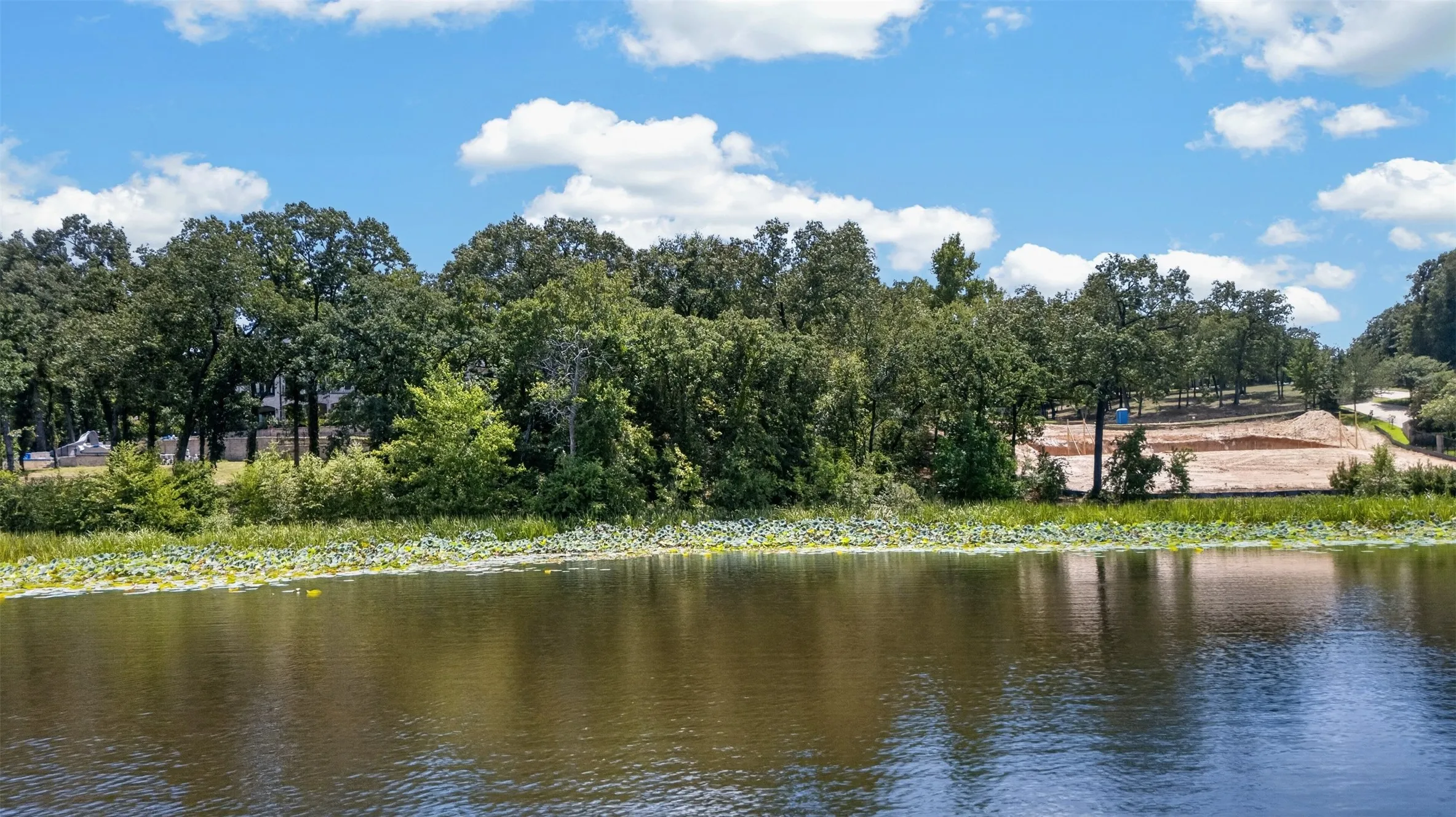 Waterfront property featuring a wooded shoreline and cleared land for development