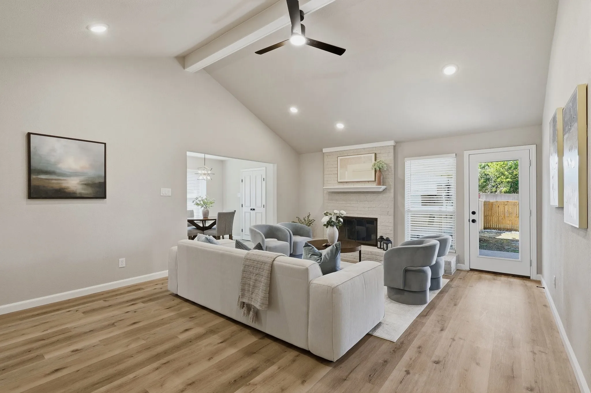 Vaulted ceiling with exposed beam, recessed lighting, wood-finish flooring, brick fireplace with mantel, and a full-light rear door