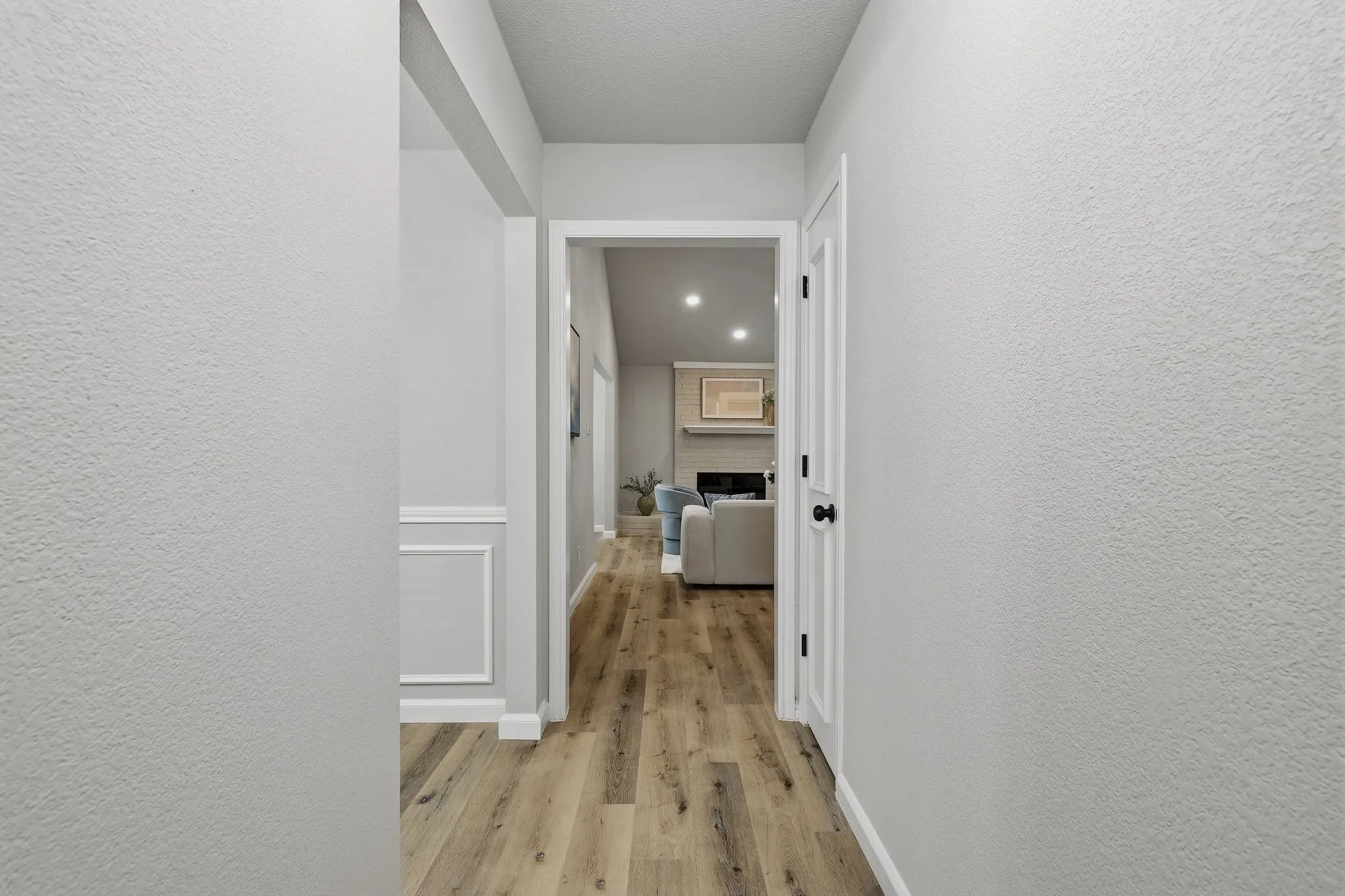 Wood-finish flooring throughout, white trim, and a white interior door with matte black hardware
