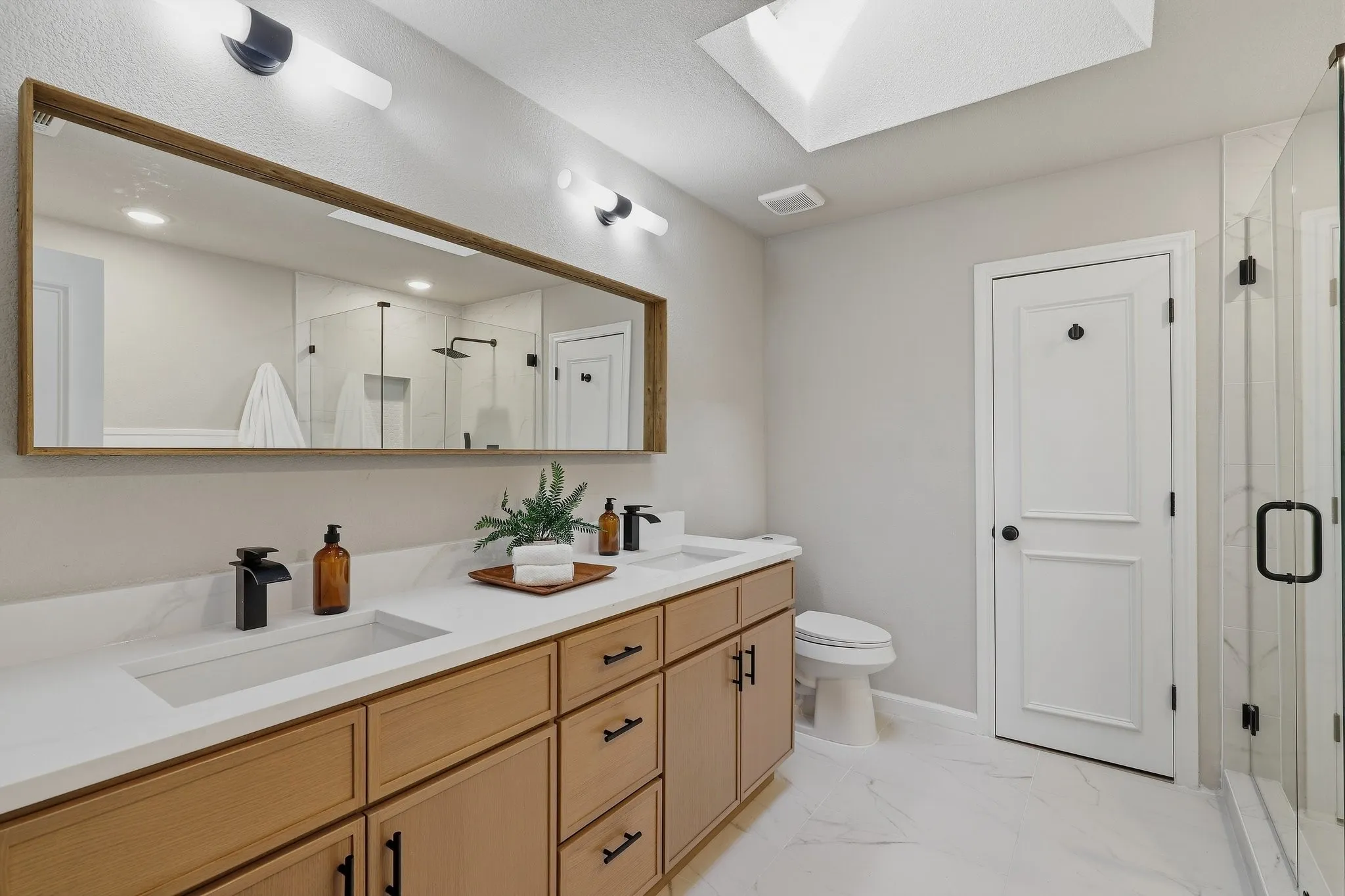 Double vanity with integrated sinks, wood-finish cabinetry, and matte black fixtures