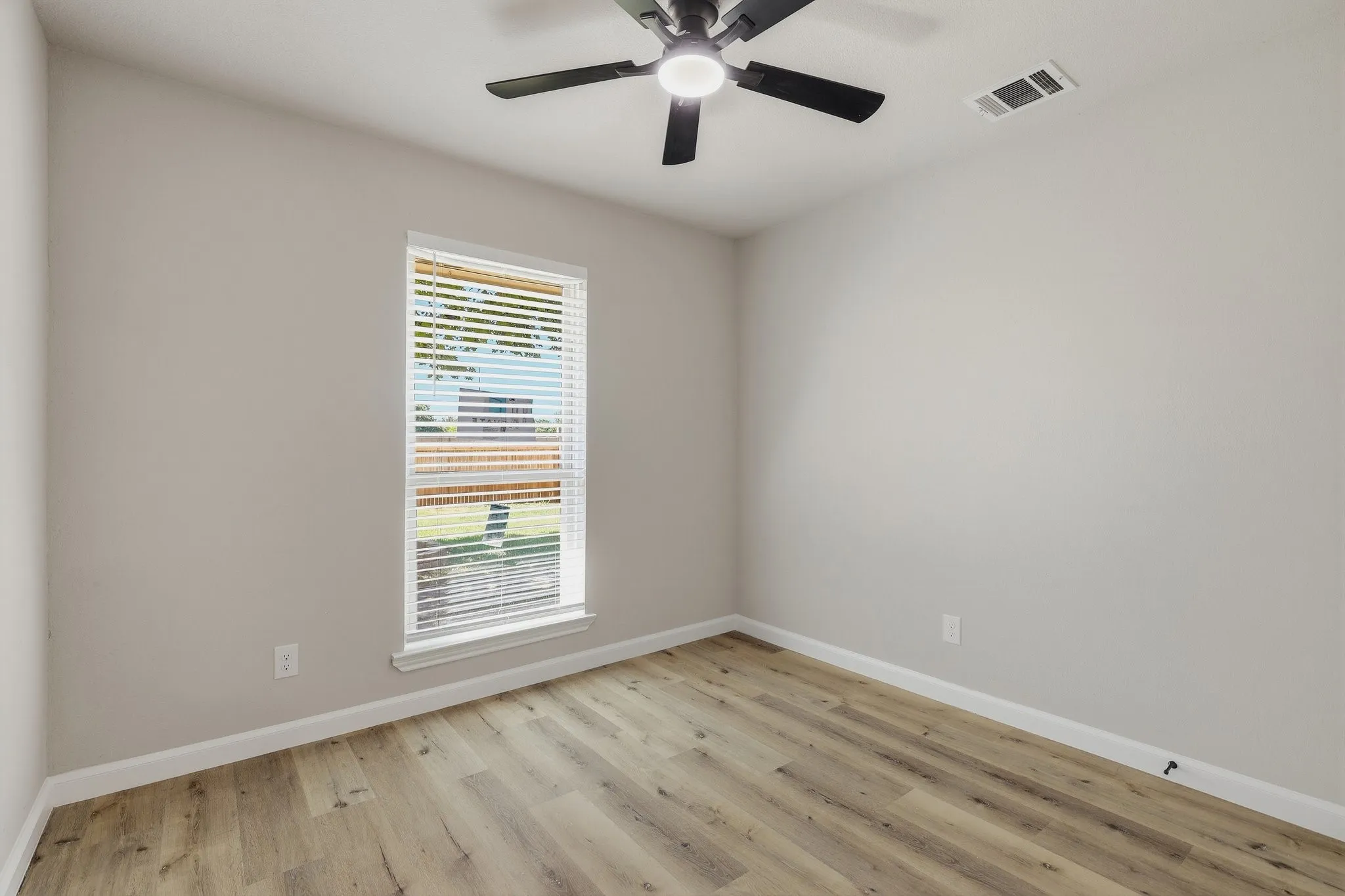 Neutral wall paint, wood-finish flooring, and a ceiling fan with integrated lighting