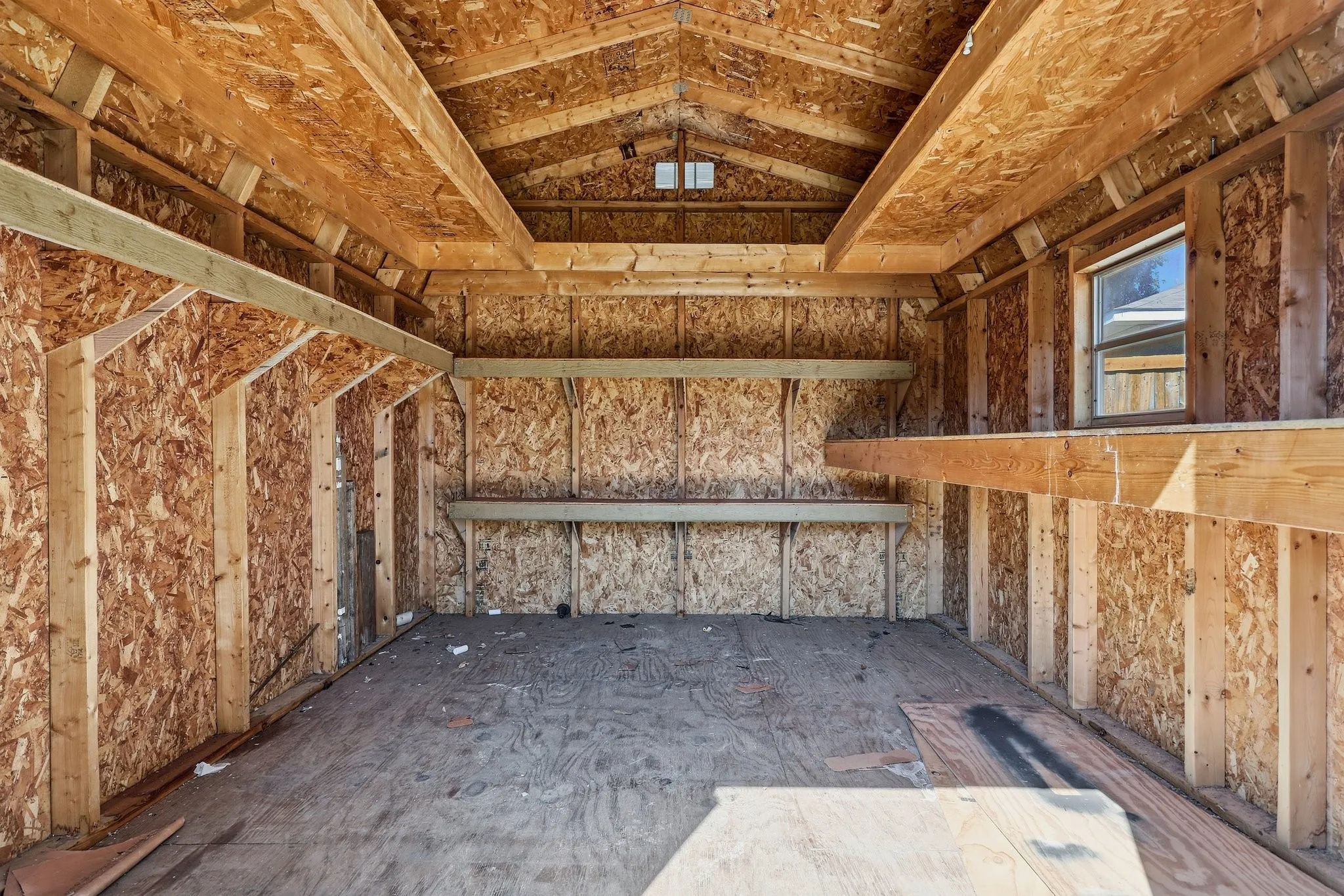Enclosed structure featuring wood-finish walls, a gabled roofline, built-in shelving, and a single window