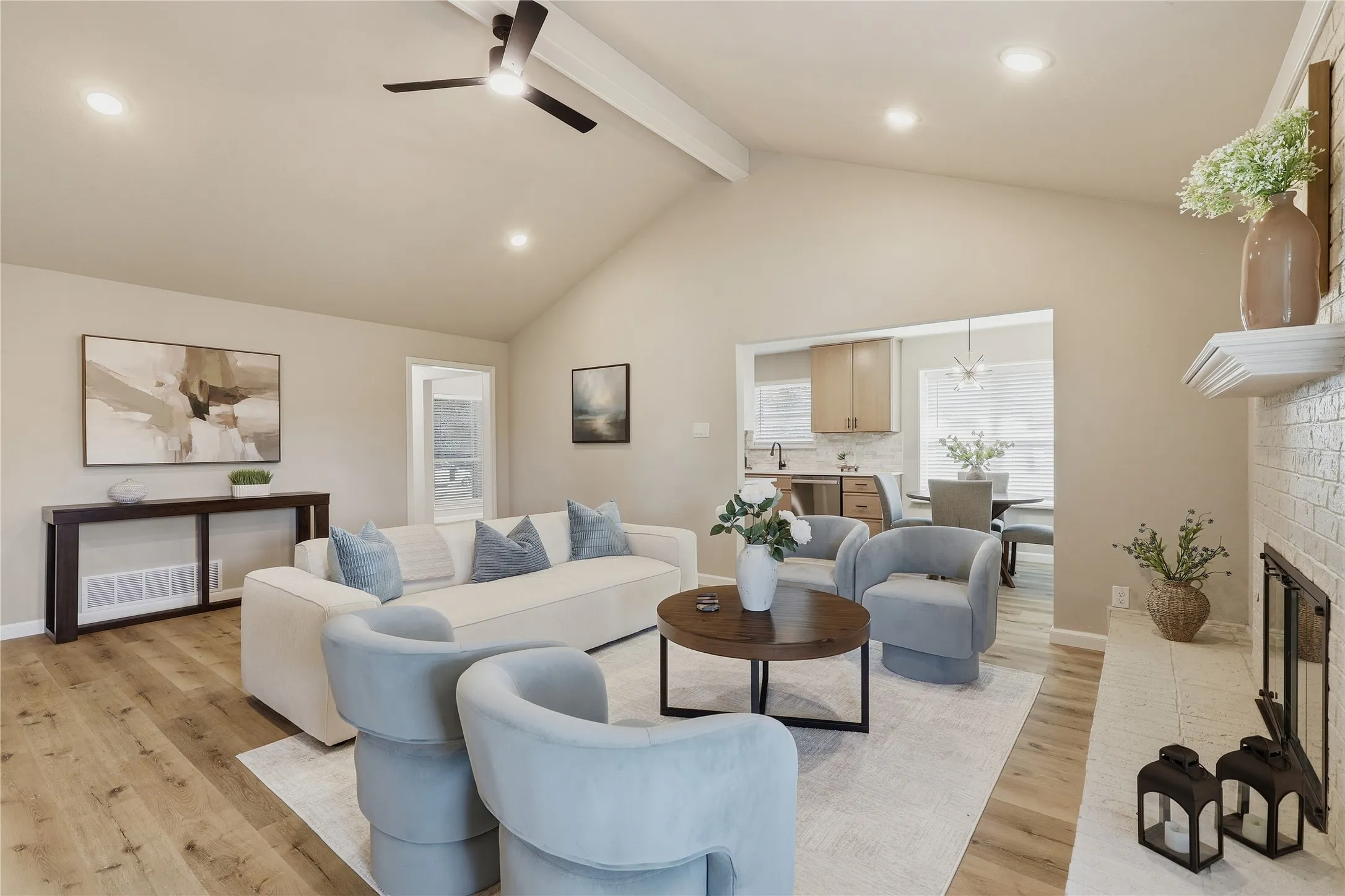 Vaulted ceilings with exposed beams, recessed lighting, wood-finish flooring, and a whitewashed brick fireplace