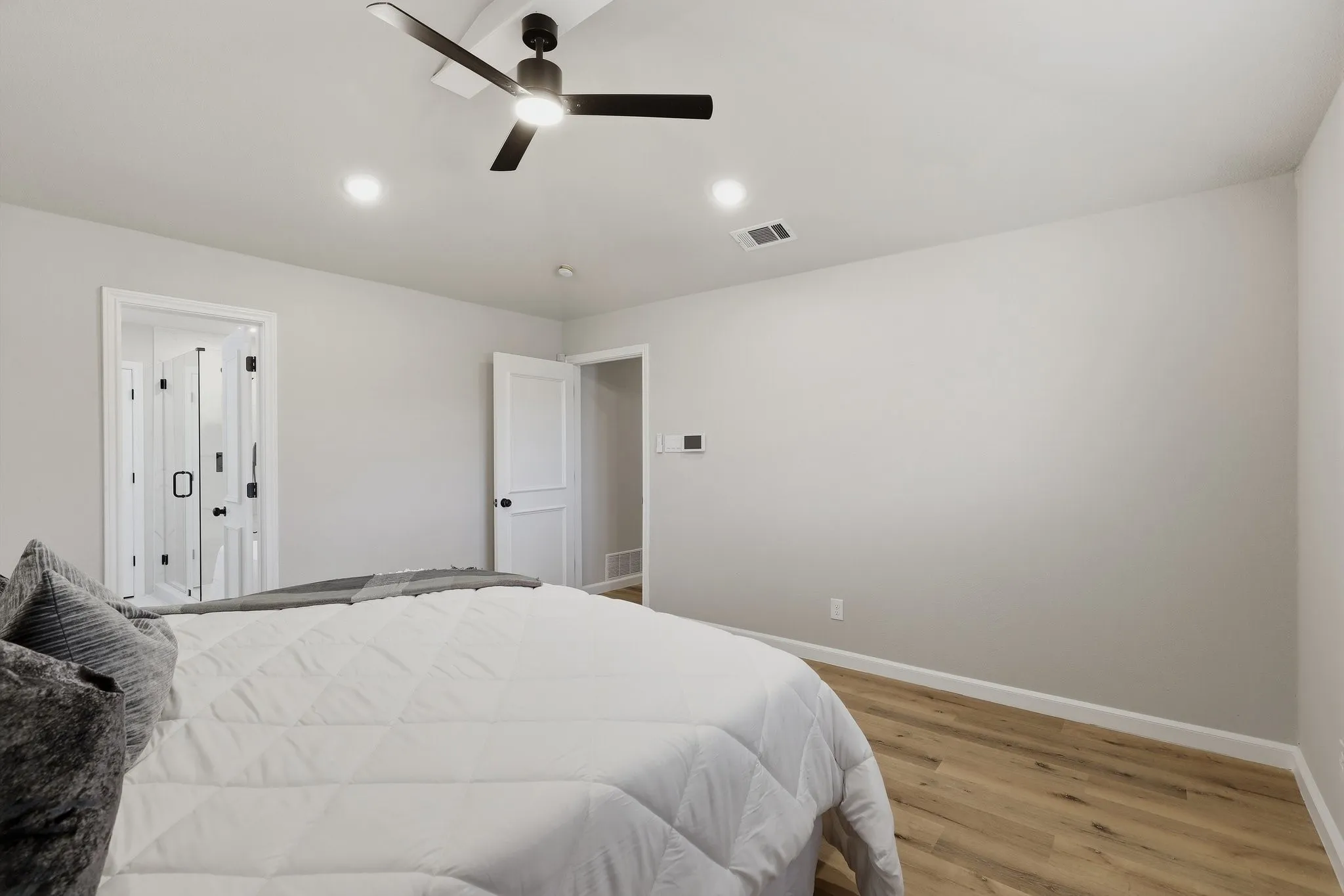 Recessed ceiling lighting, a ceiling fan, wood-finish flooring, and painted interior doors with dark hardware