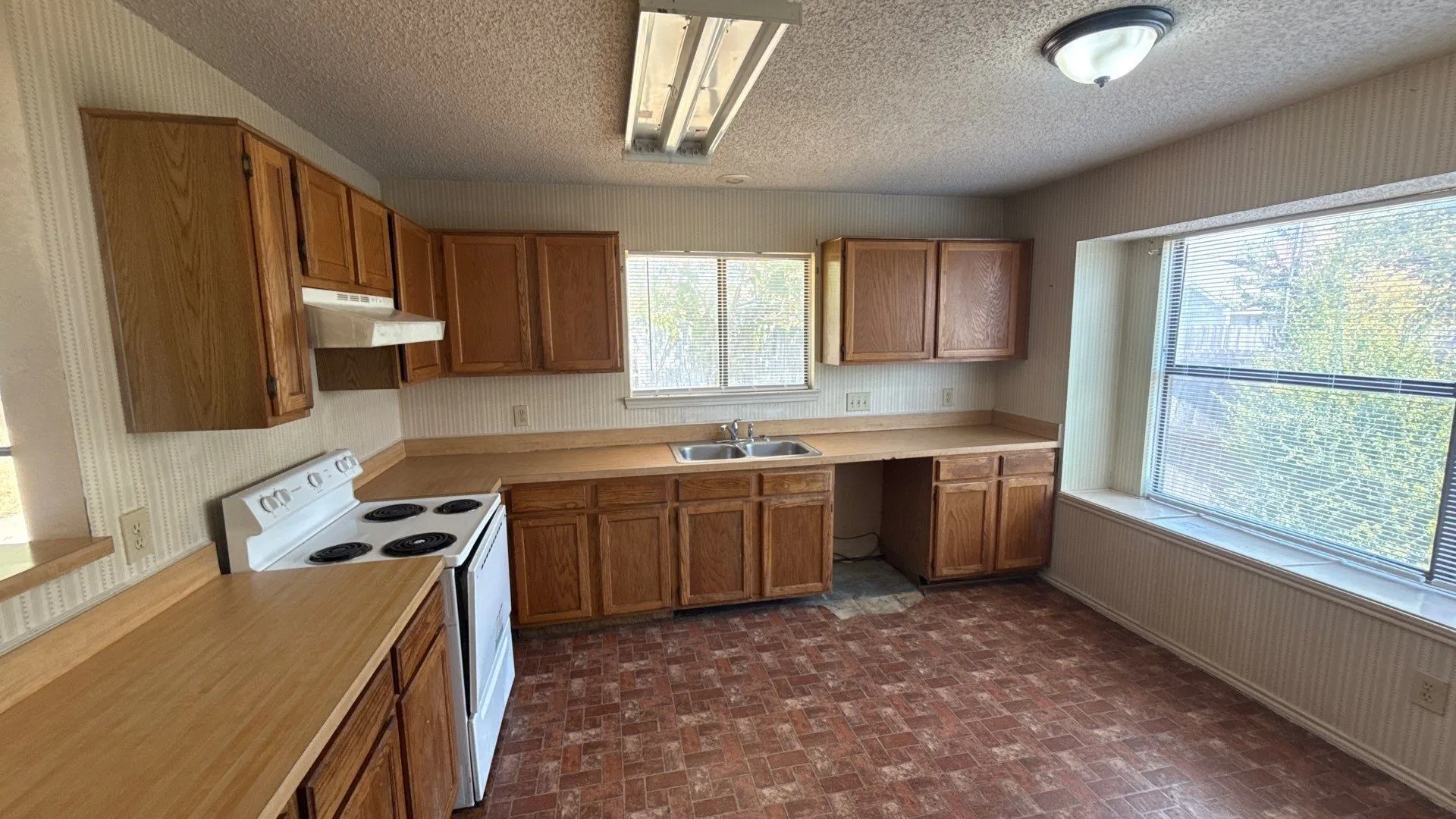Wood-finish cabinetry with abundant storage, wood-finish countertops, and a built-in double basin sink