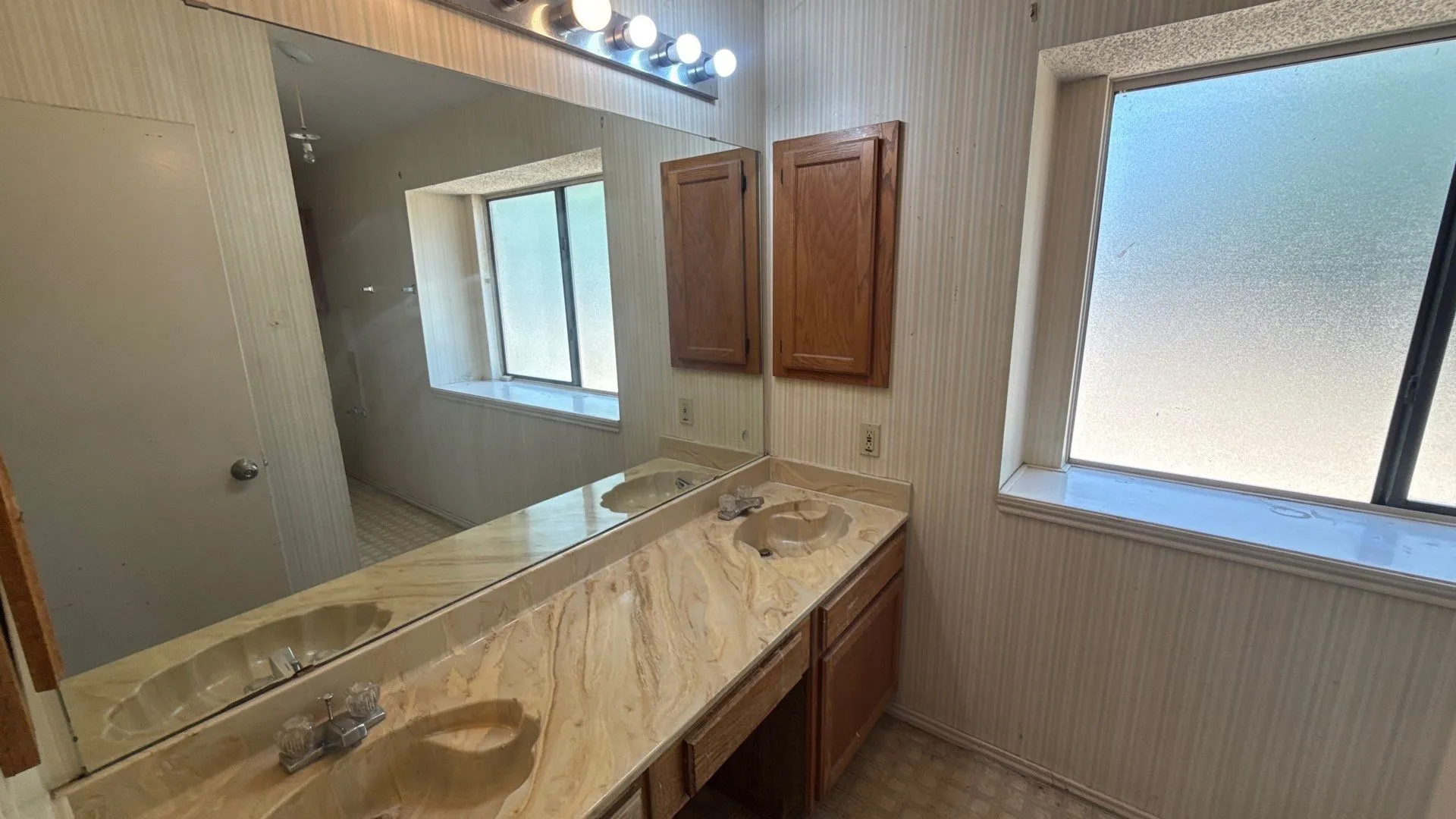 Dual vanity with integrated sinks, expansive wall-mounted mirror, and wood-finish cabinetry