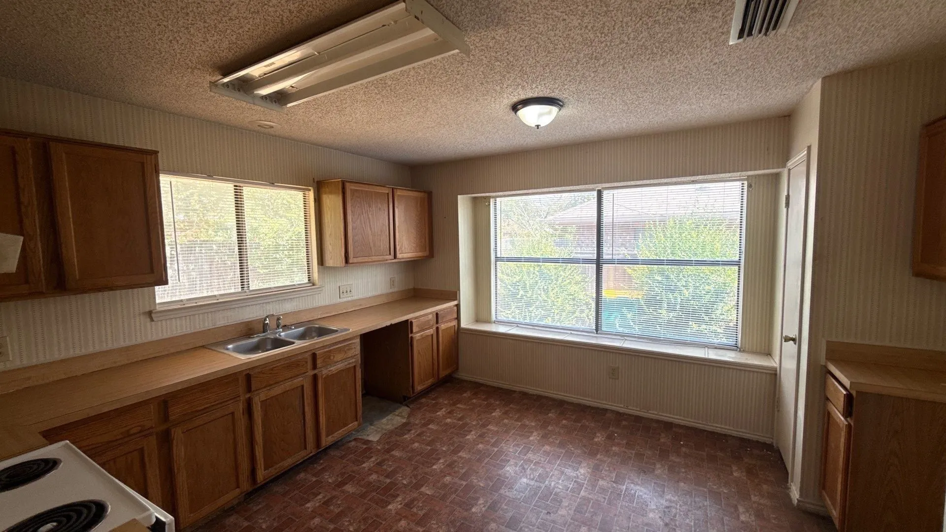 Kitchen featuring wood cabinetry, laminate countertops, a double-basin stainless steel sink, and a window over the sink